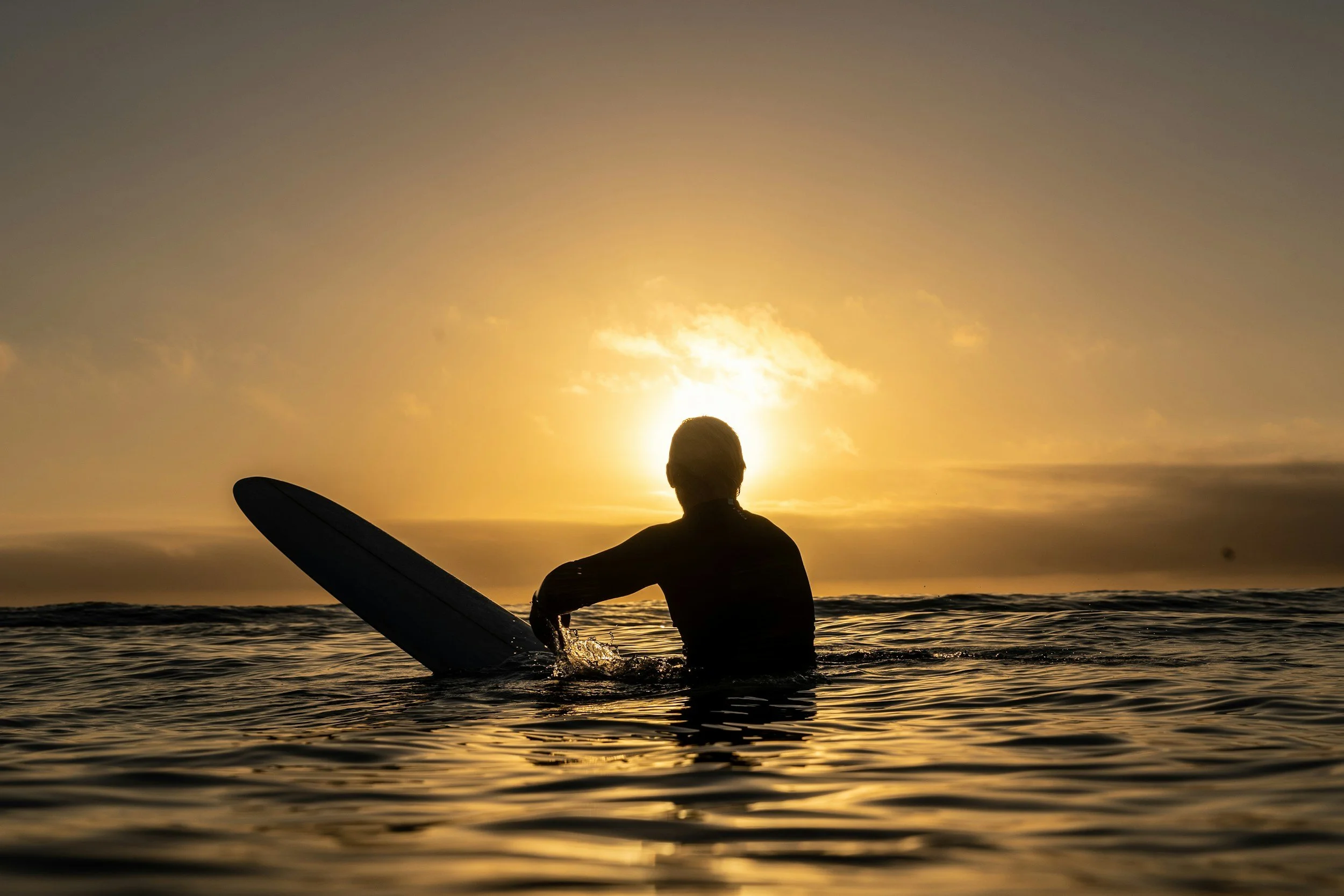 Athletic surfer popping up on a wave at sunset, showcasing surf fitness and performance