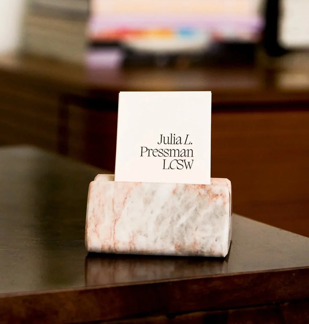 Name card with Julia L. Pressman LCSW on a marble holder on a dark wooden surface