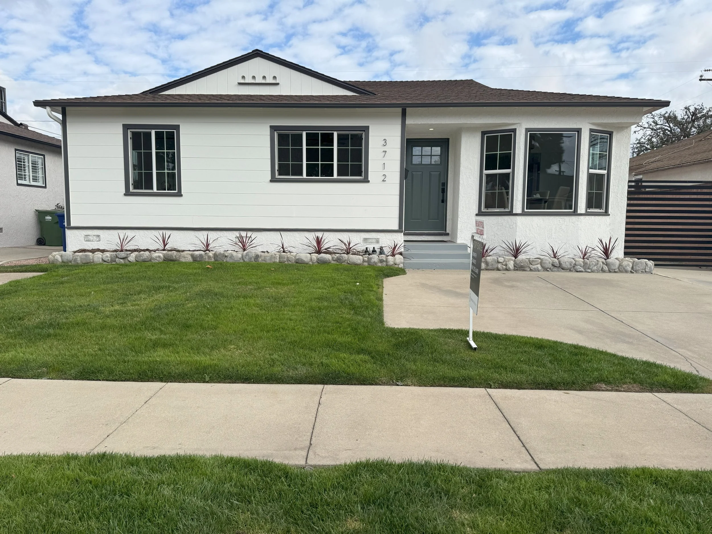 Before photo: grass lawn and small planting bed along house with concrete driveway/path