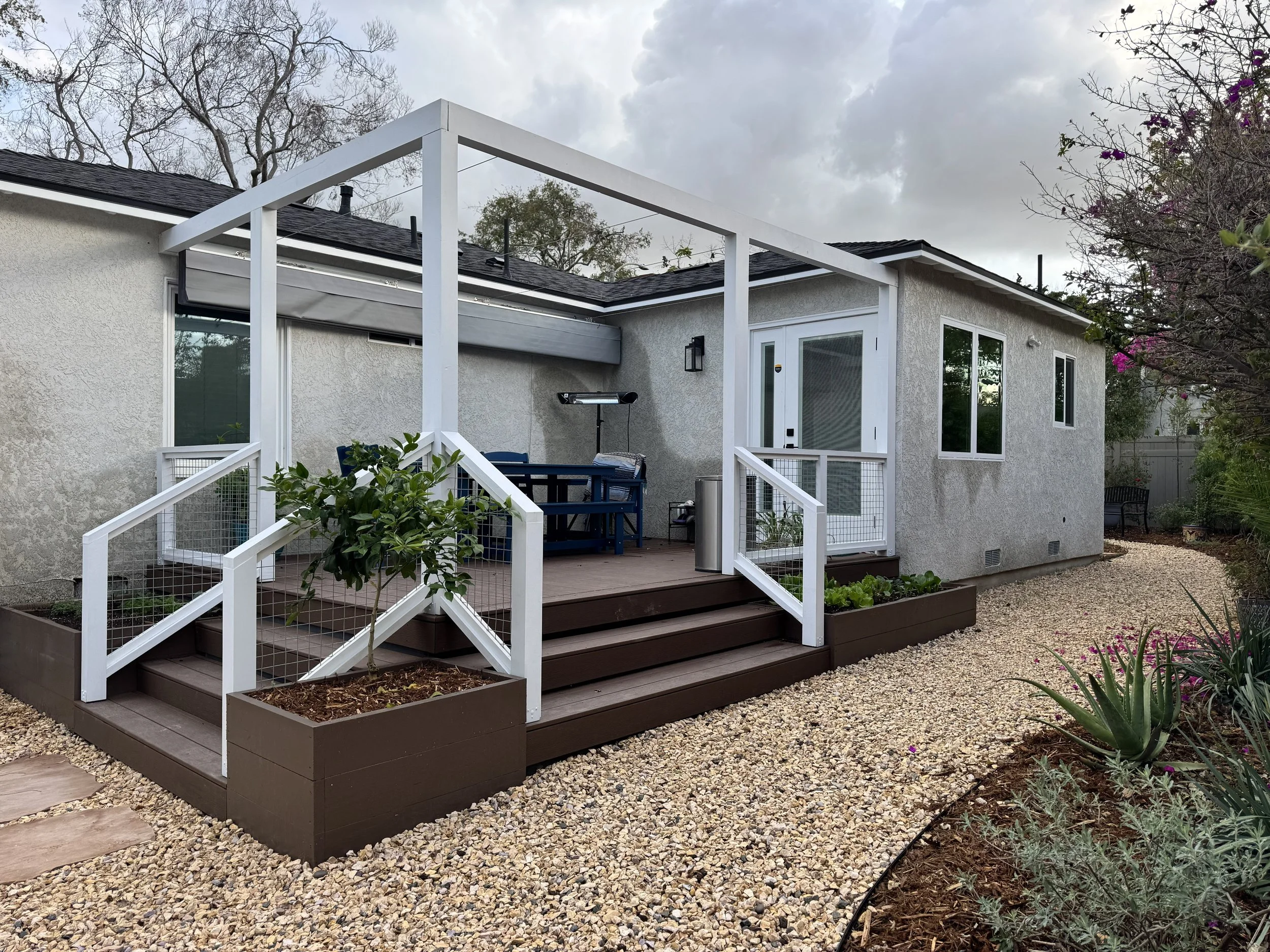 Mid-tier backyard remodel in Long Beach CA with deck, pergola, gravel ground cover, and drought-tolerant landscaping.