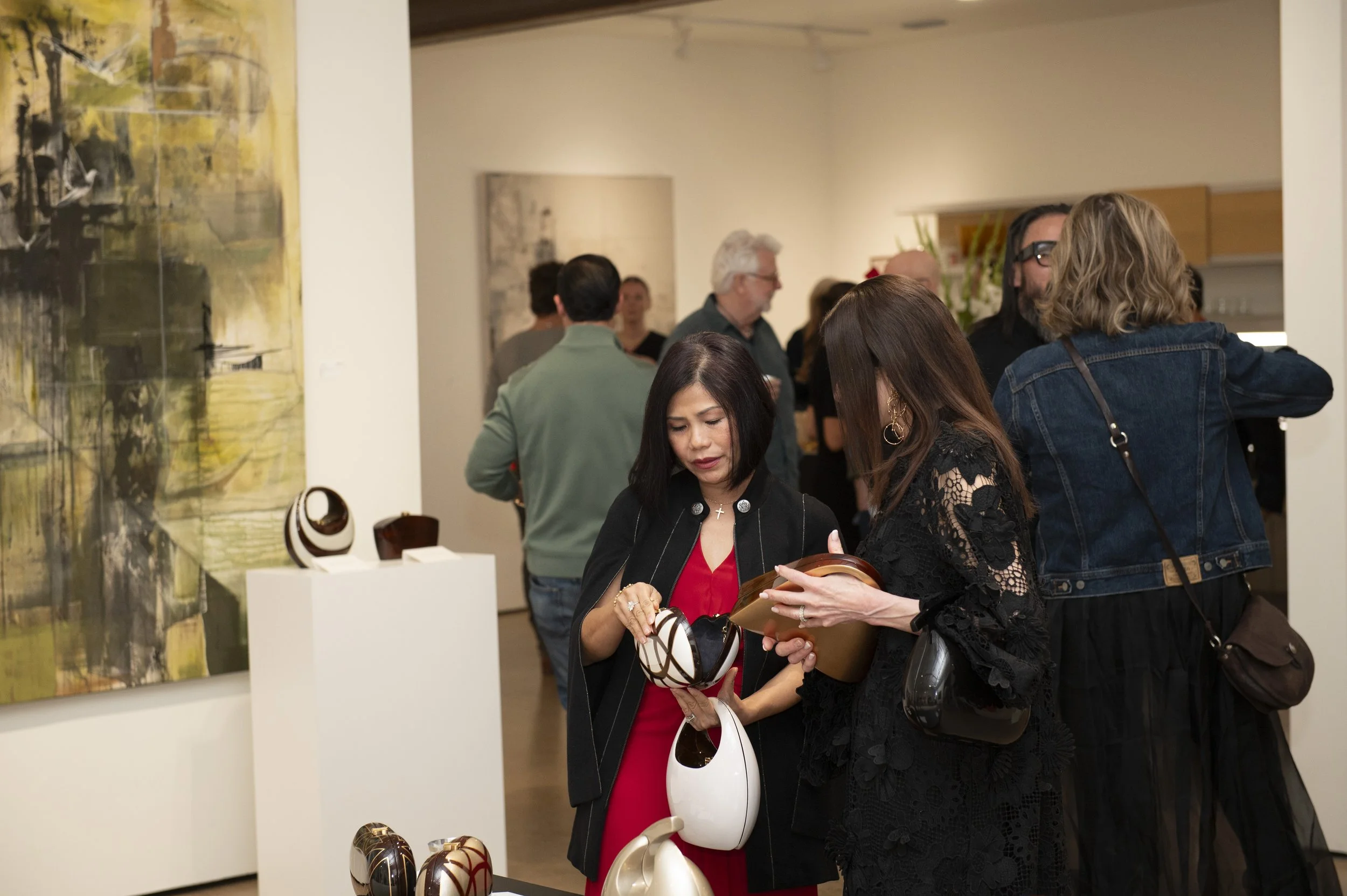 People browsing artwork and sculptures at an art gallery opening.