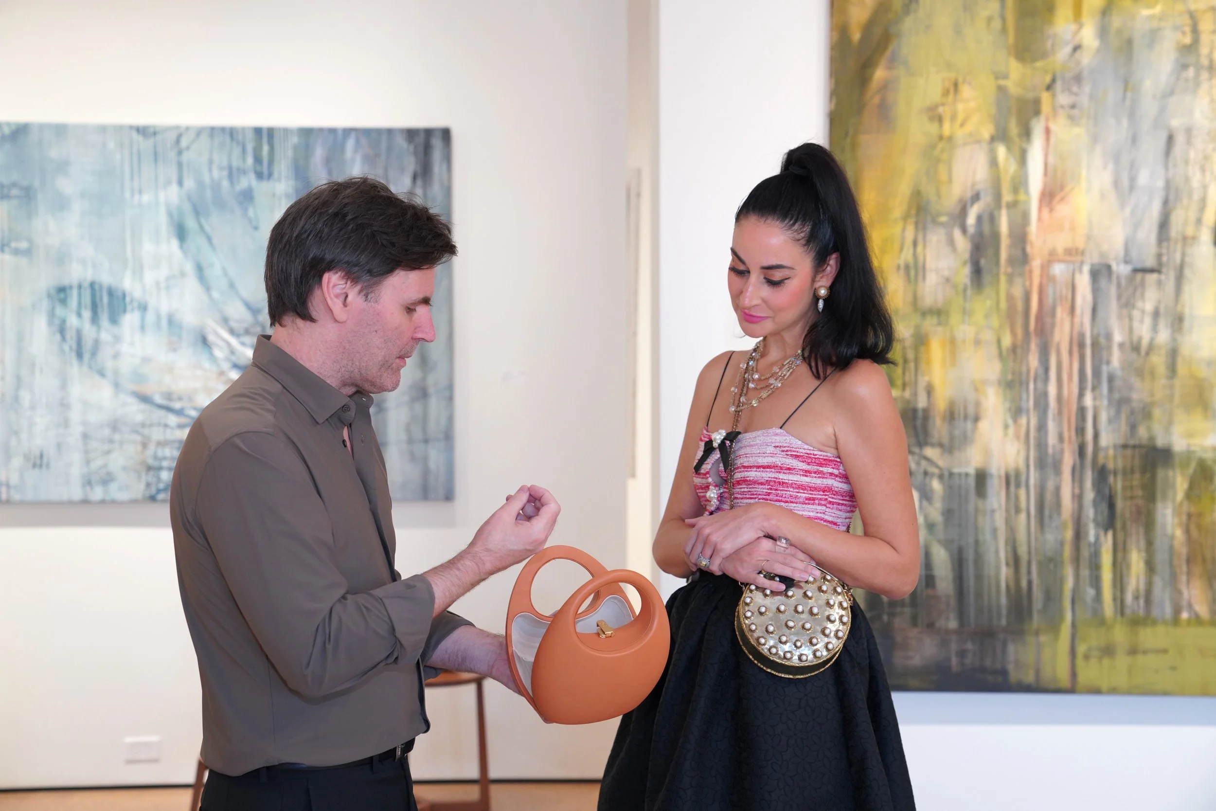 A man showing a ring to a woman in an art gallery.