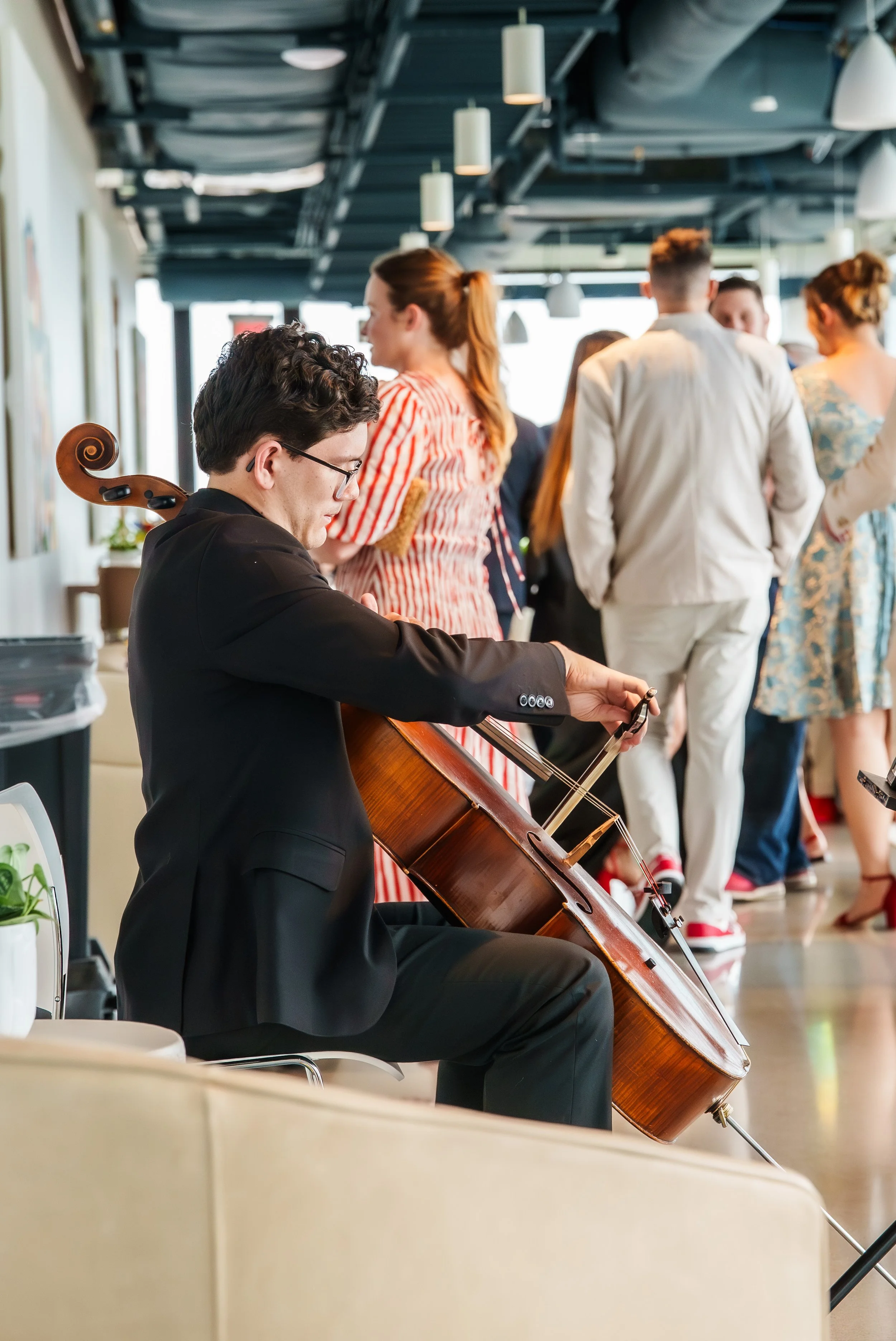 Event photography of a man playing his cello at a Ronald McDonald House event at the Ledger in Bentonville Arkansas.