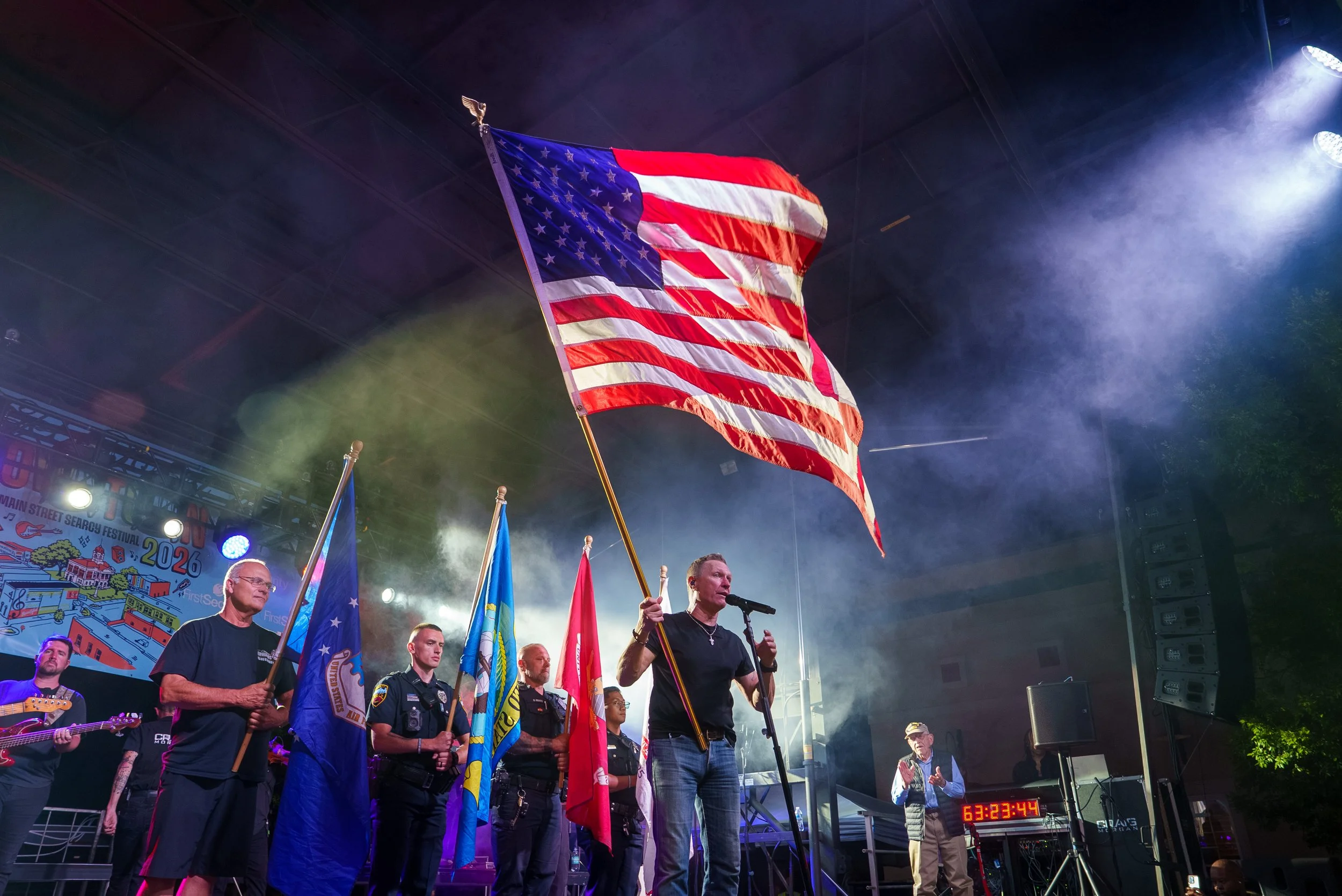 Event photography of country singer Craig Morgan singing and waving a flag at a concert in Searcy Arkansas.
