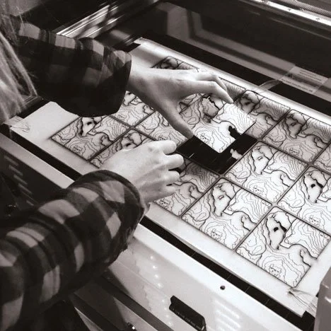 Debbie Joy taking freshly cut coasters out of a laser machine.