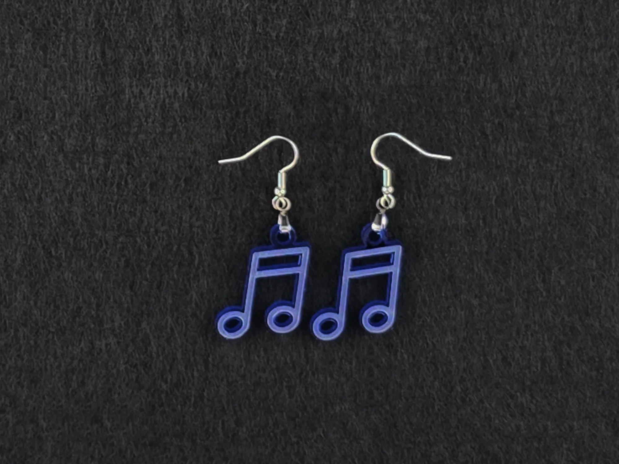 Pair of blue acrylic beam note earrings on stainless steel ear wires, flat lay on a charcoal background.