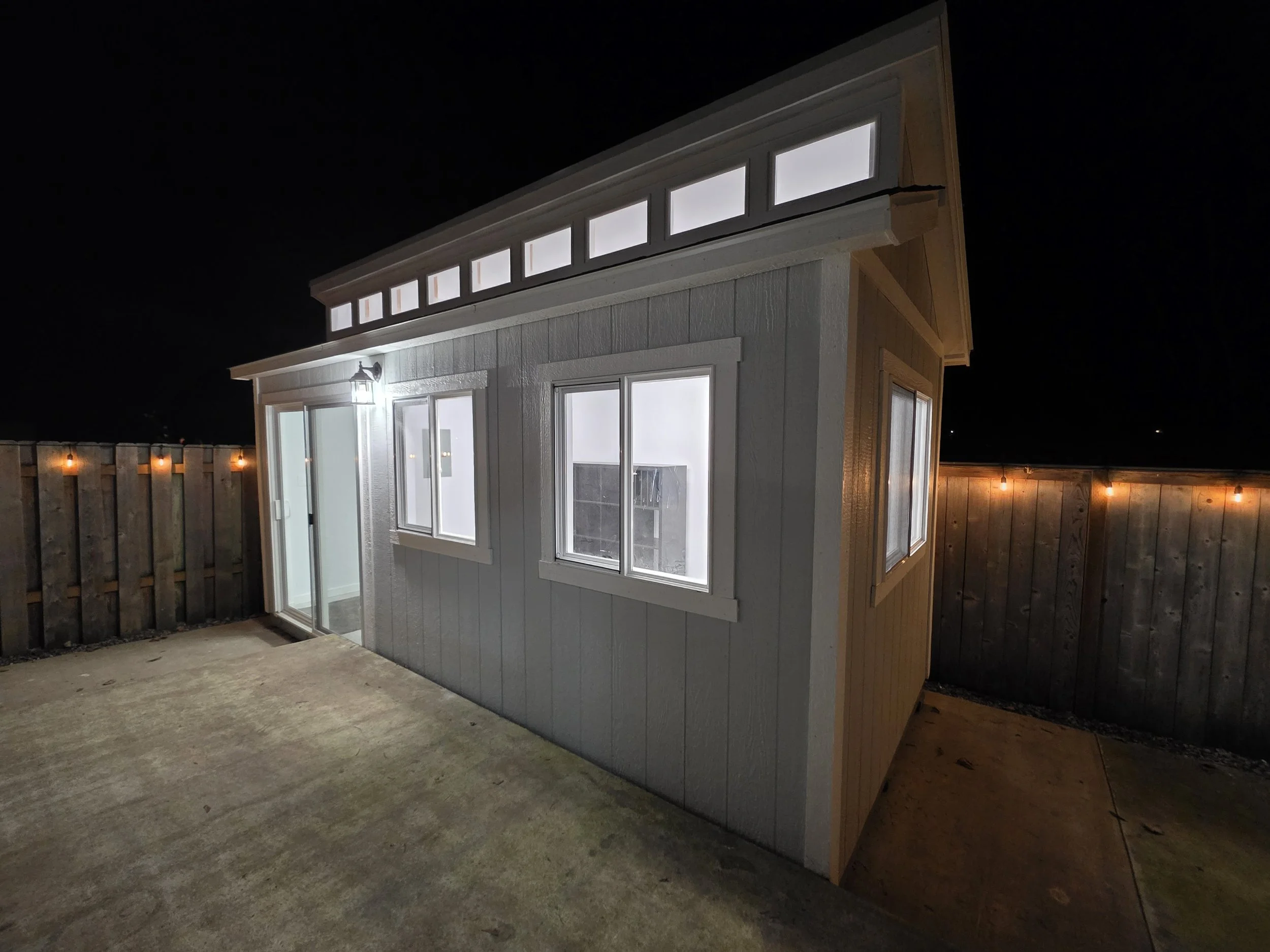 Exterior of the Rainbow Charlie studio at night, with interior lights glowing through the windows.