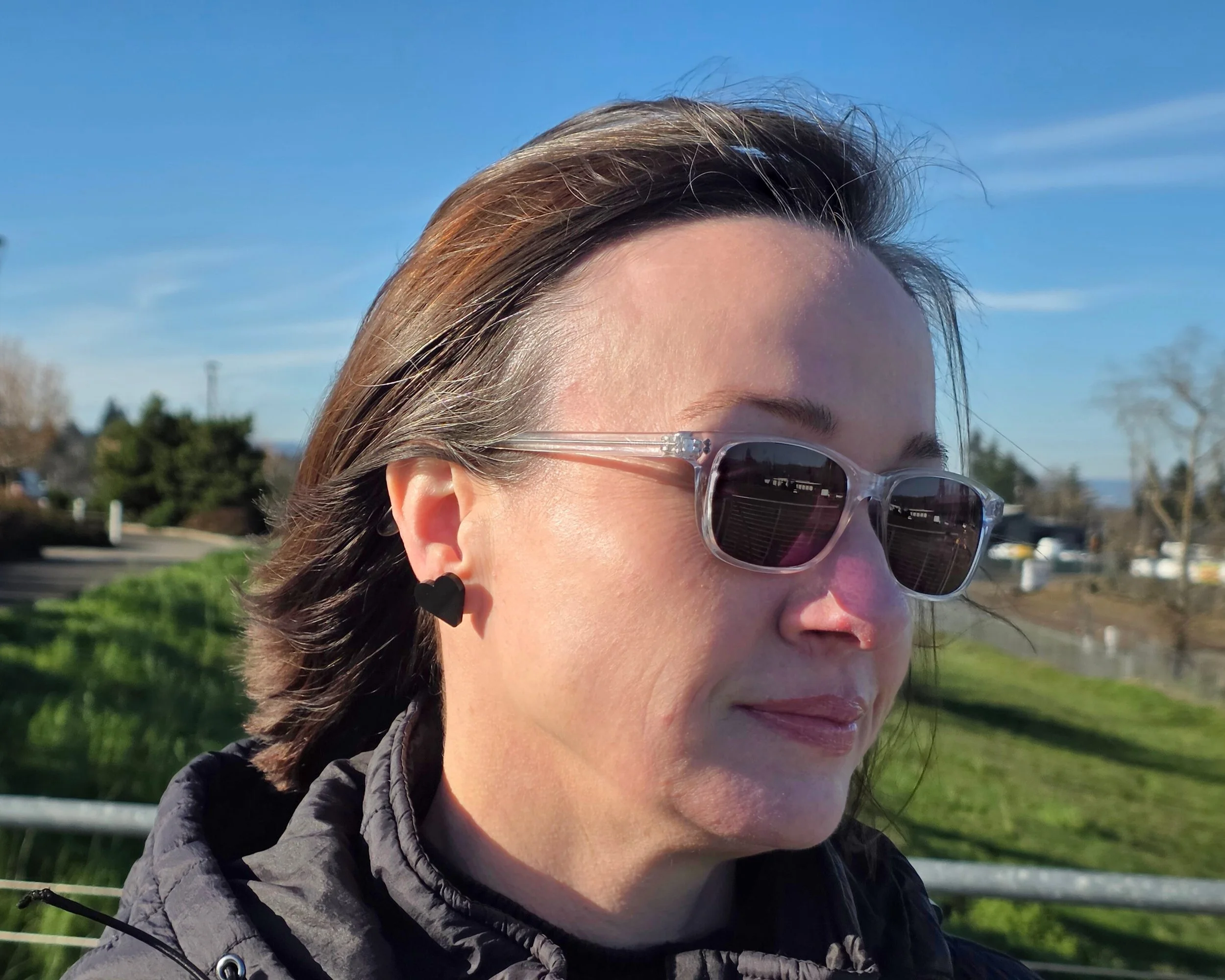 Black acrylic heart stud earring worn outdoors, side view showing fit and scale, lightweight hypoallergenic earrings for sensitive ears