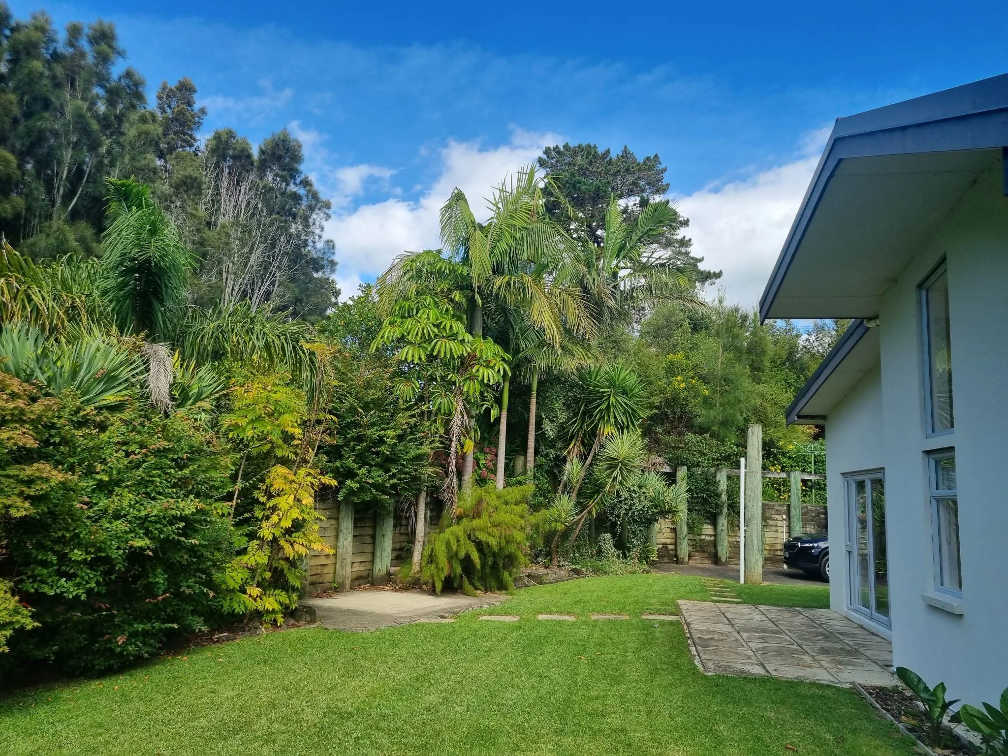 Outdoor patio with wicker furniture, a grill, and an umbrella next to a house. A grassy yard extends to the right with a fence and landscaping. A small dog is visible on the grass, at Keystone Lodge