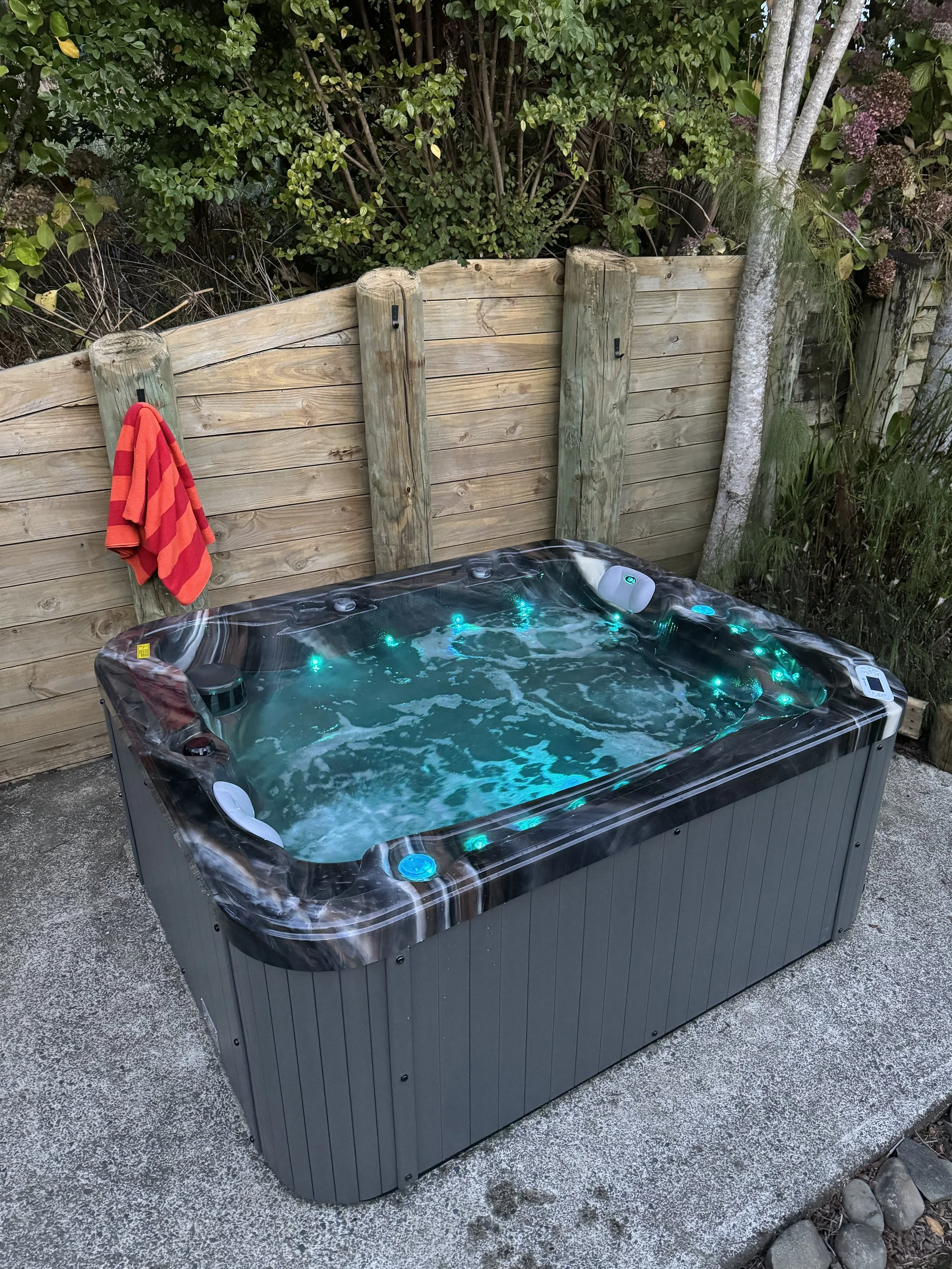 Backyard with hot tub, wooden fence, red towels, and garden plants, at Keystone Lodge