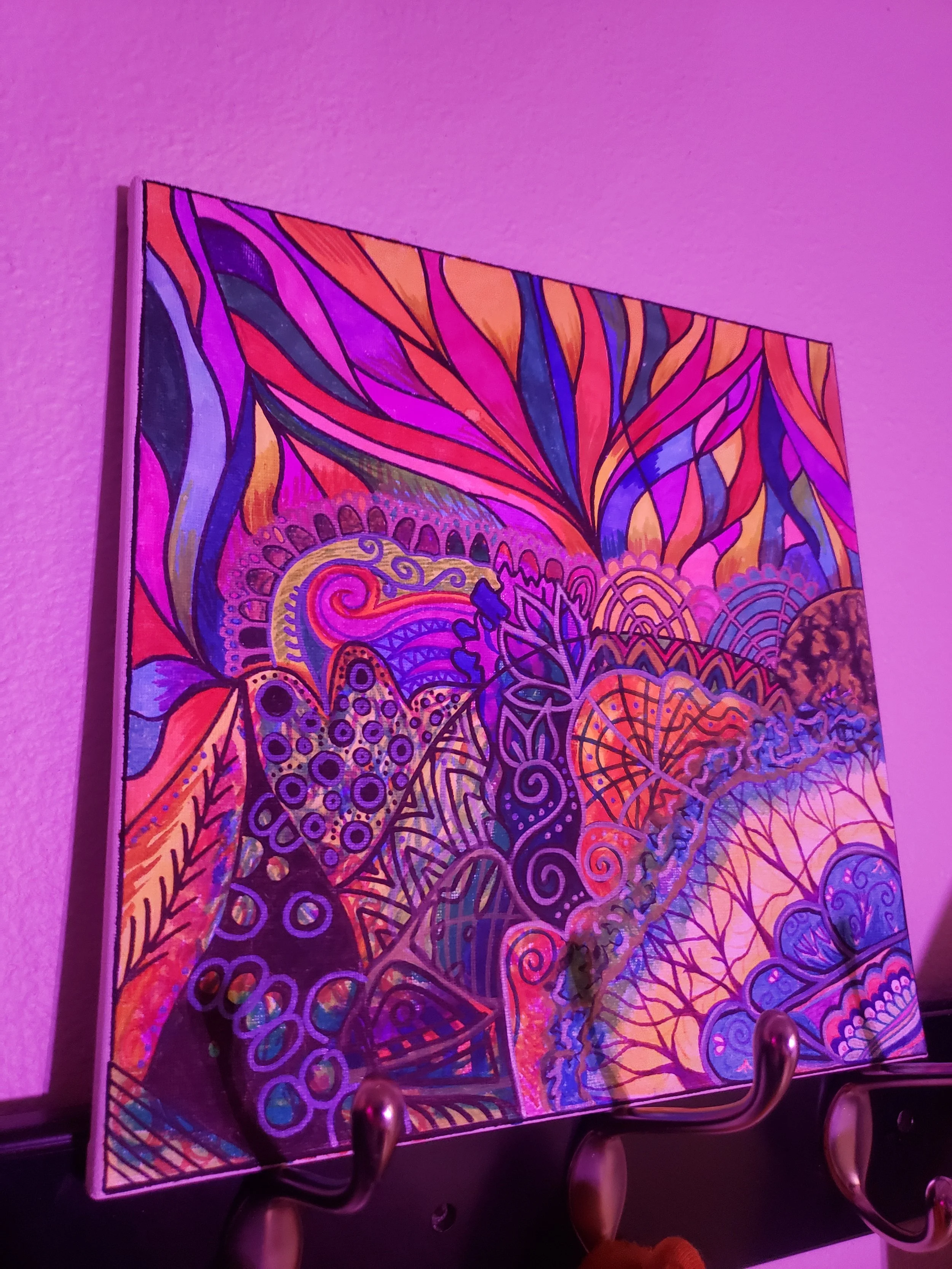 Colorful abstract painting with vibrant swirling patterns and leaf motifs, illuminated by purple lighting.