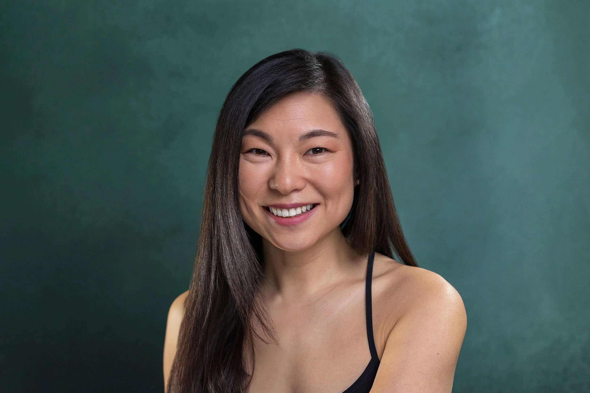 Female actor headshot London. Commercial look, warm natural smile, teal background, shot by Andrew