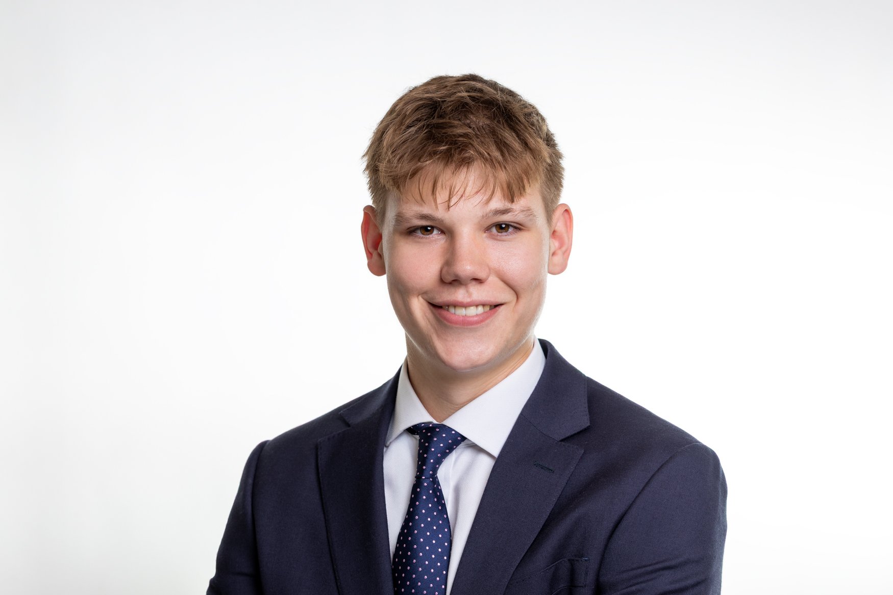 Professional headshot of a young man in a navy suit, taken in London by Shot By Andrew