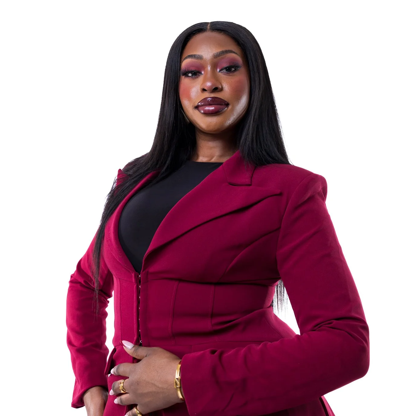 Woman with long dark hair in a burgundy blazer over a black top, hand on hip with a confident expression on a white background | Business headshots London | Shot By Andrew