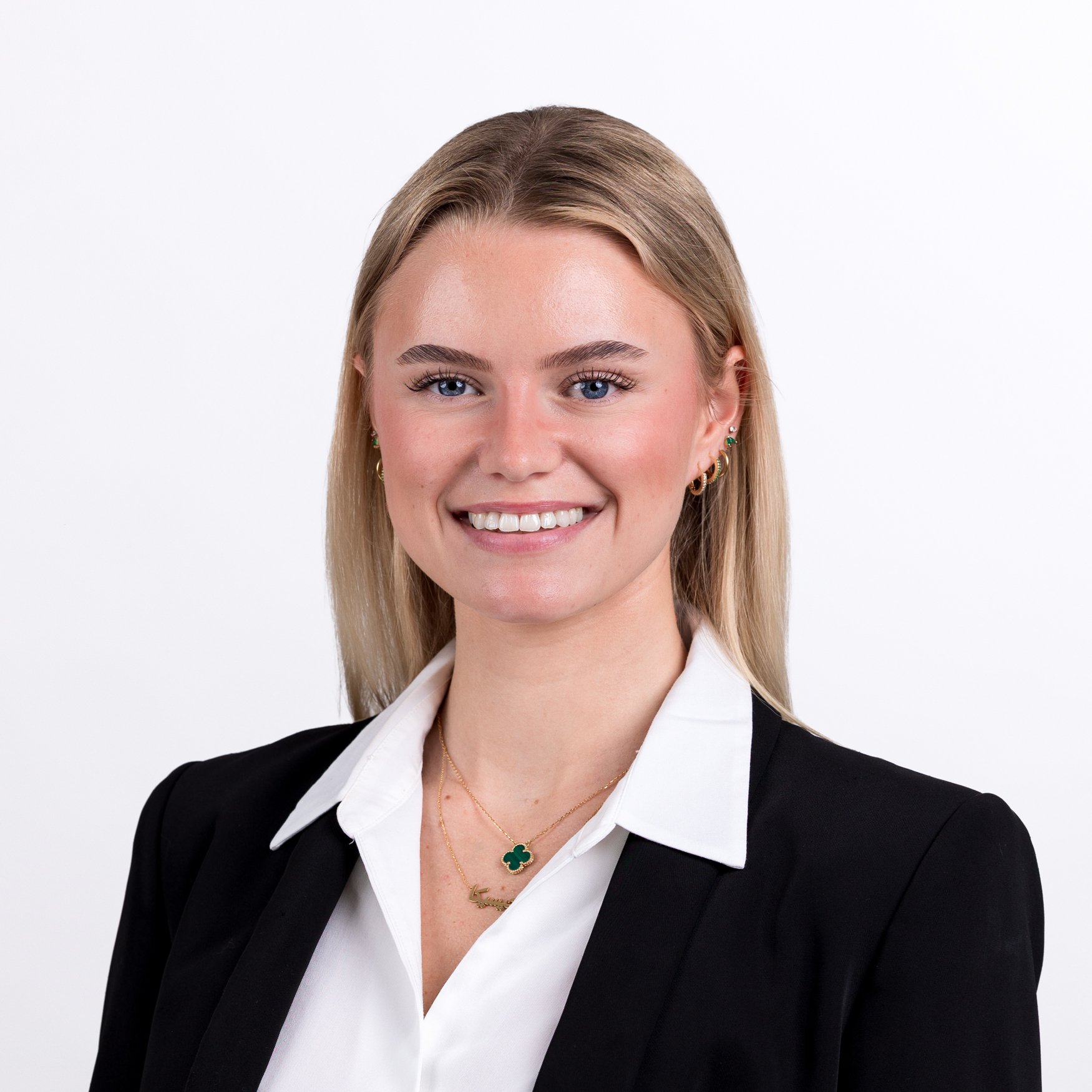 Corporate headshot of a smiling blonde woman in a black blazer and white shirt, grey studio background | Corporate headshots Victoria, London | Shot By Andrew