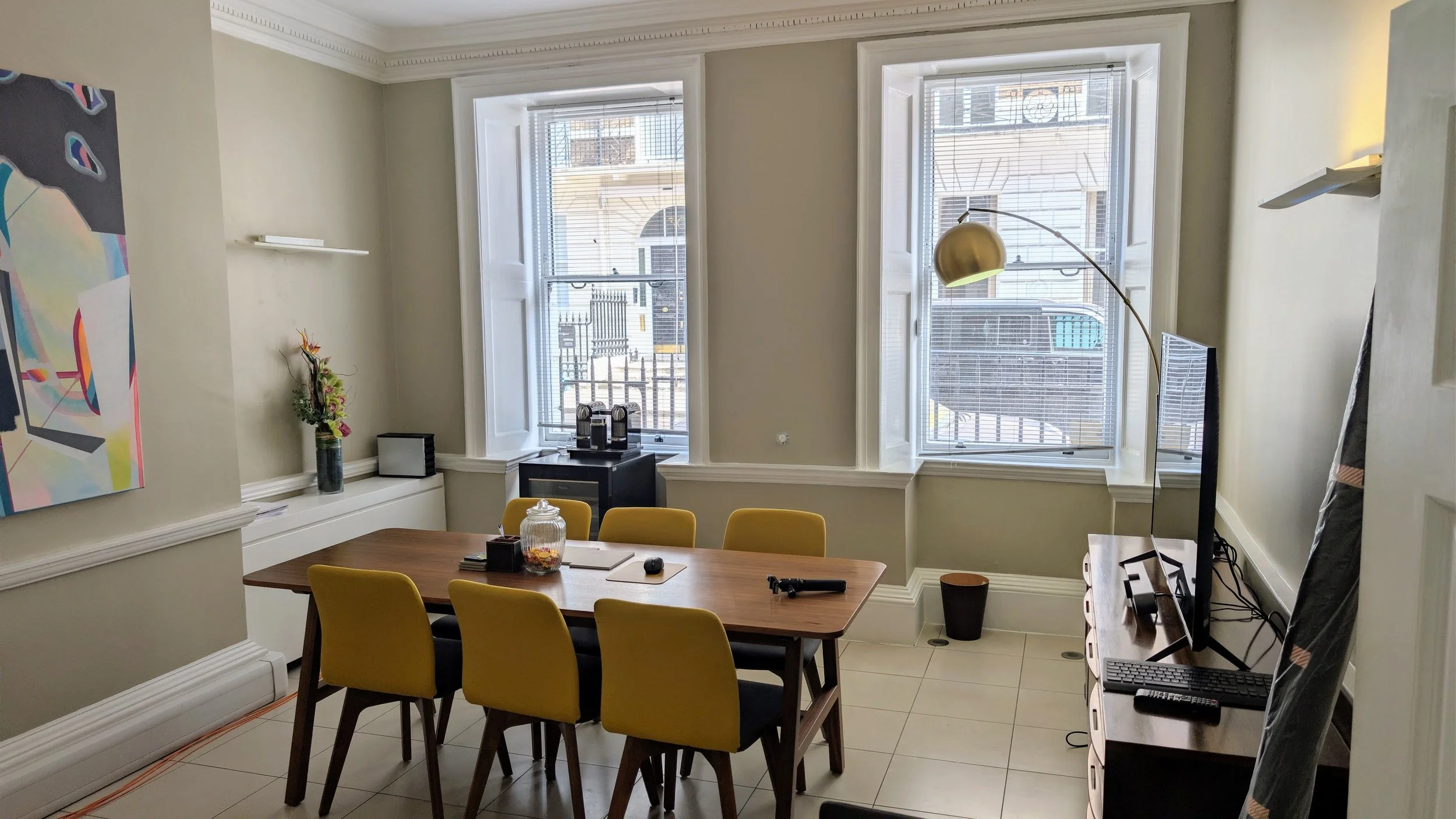 Empty office meeting room with a wooden boardroom table and mustard chairs before the studio is built | On-location corporate headshots London | Shot By Andrew
