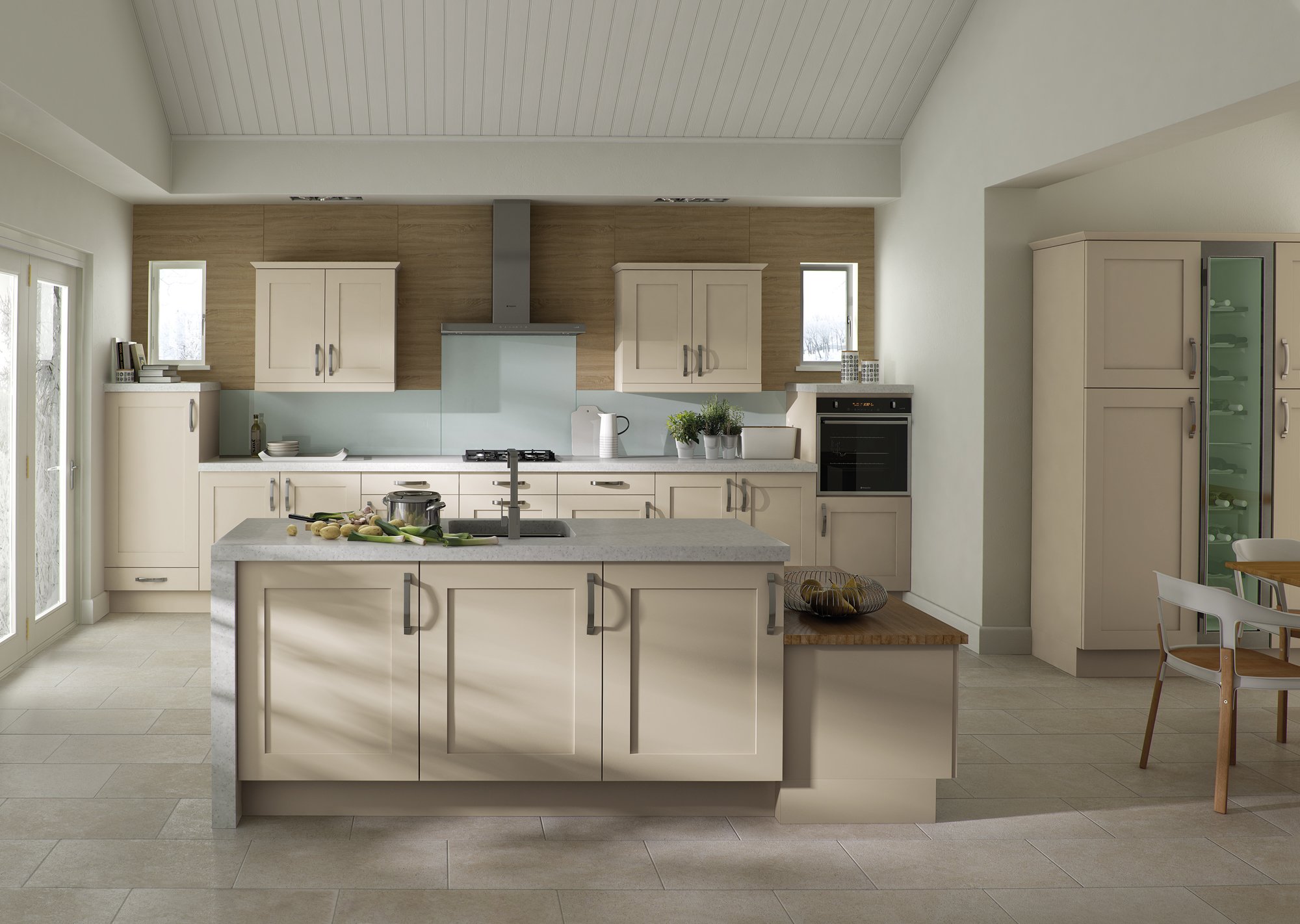 Modern kitchen with cream cabinets, central island, stainless steel fixtures, and a built-in oven. Light tile flooring and large windows provide natural lighting.