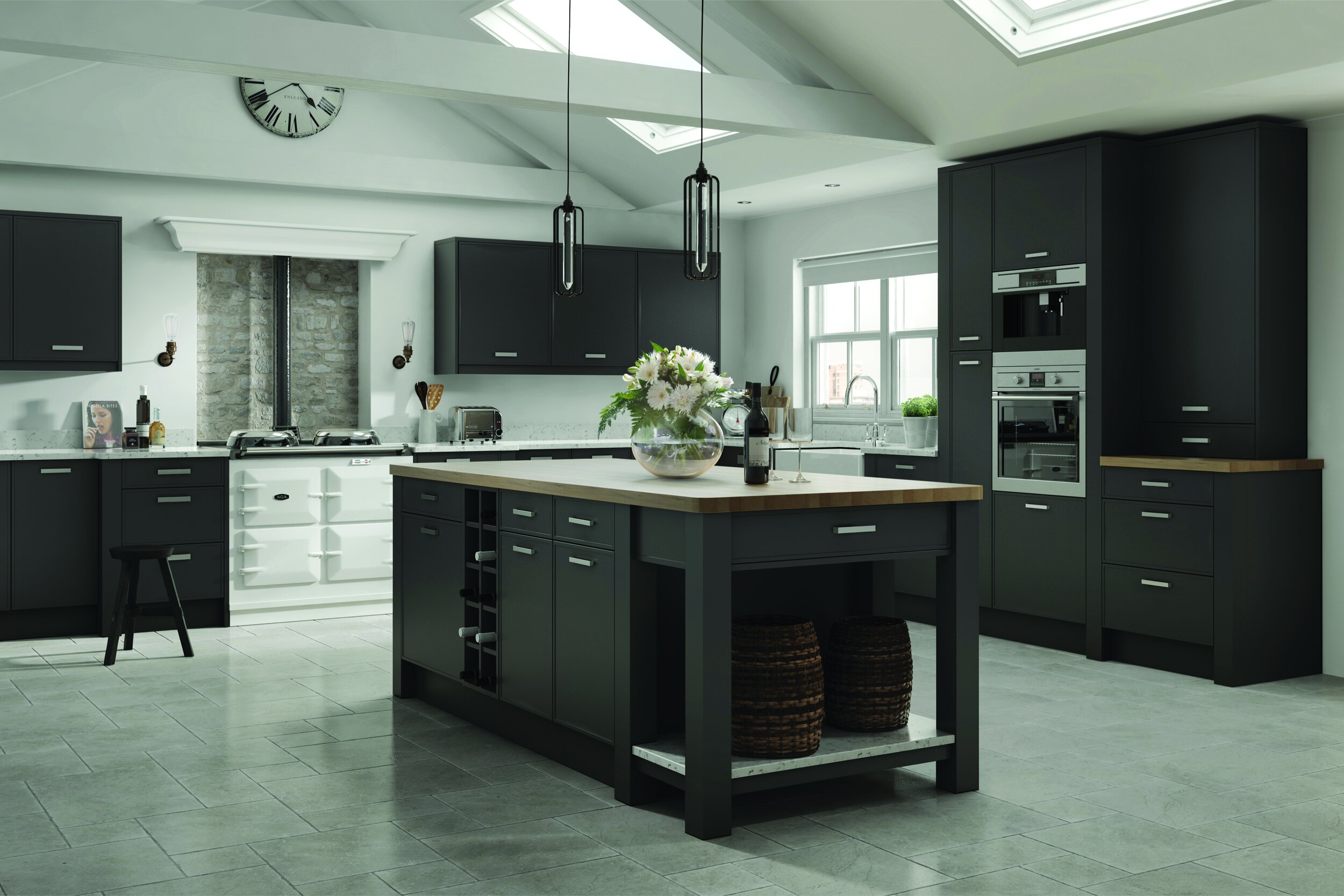Modern kitchen with black cabinets, large island with wood countertop, hanging pendant lights, white oven, and skylights.