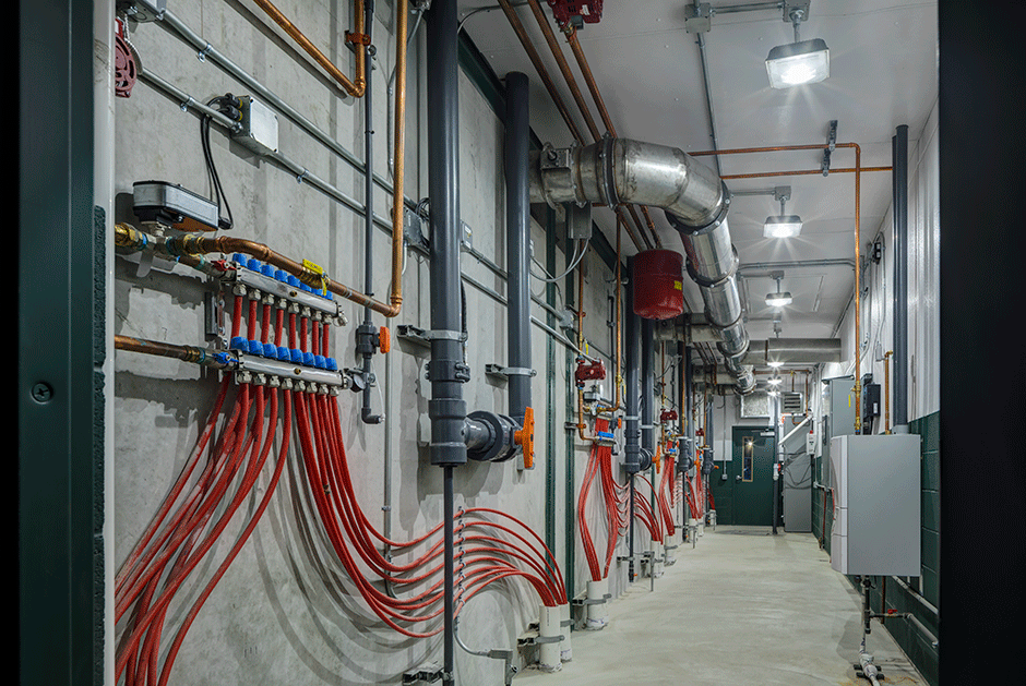 Industrial basement with pipes, valves, and electrical panels.