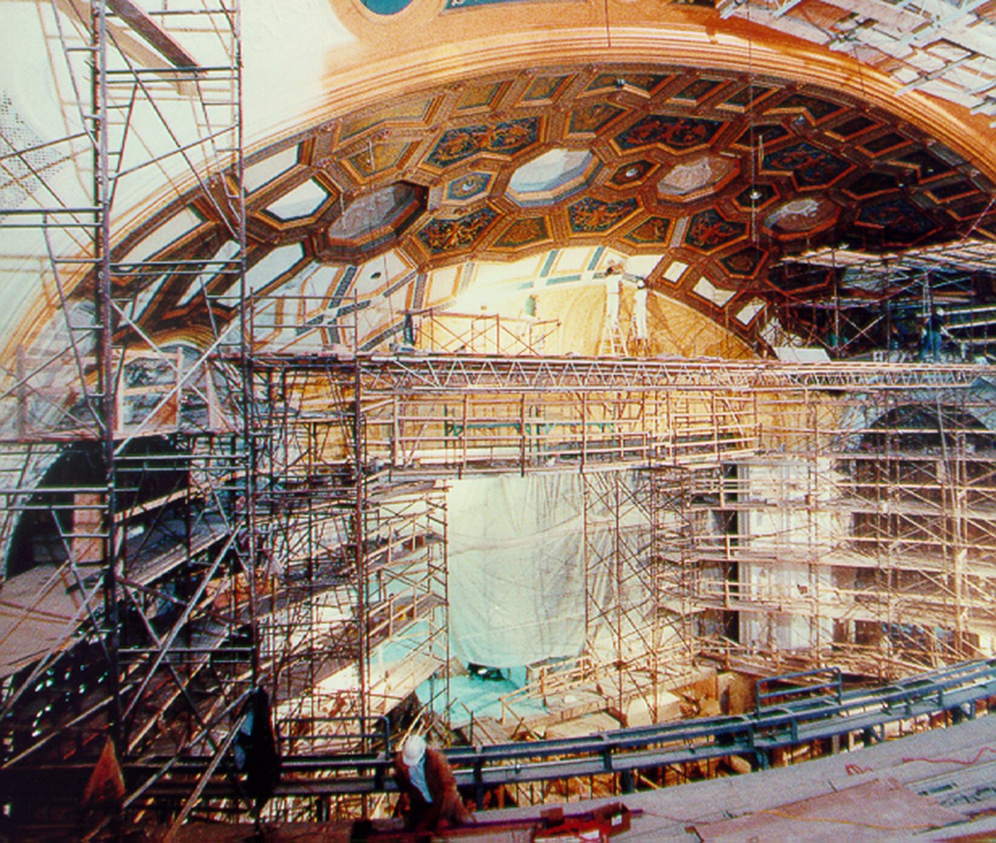 Interior of a building under construction with scaffolding and ornate ceiling details.