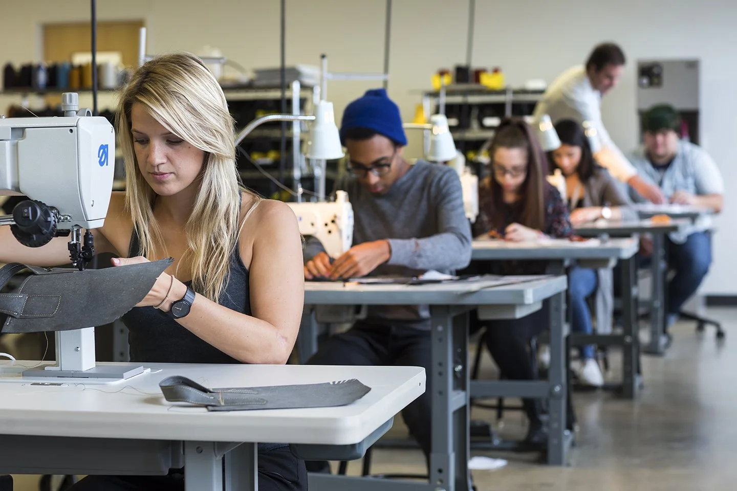 A group of students working on sewing projects in a classroom.