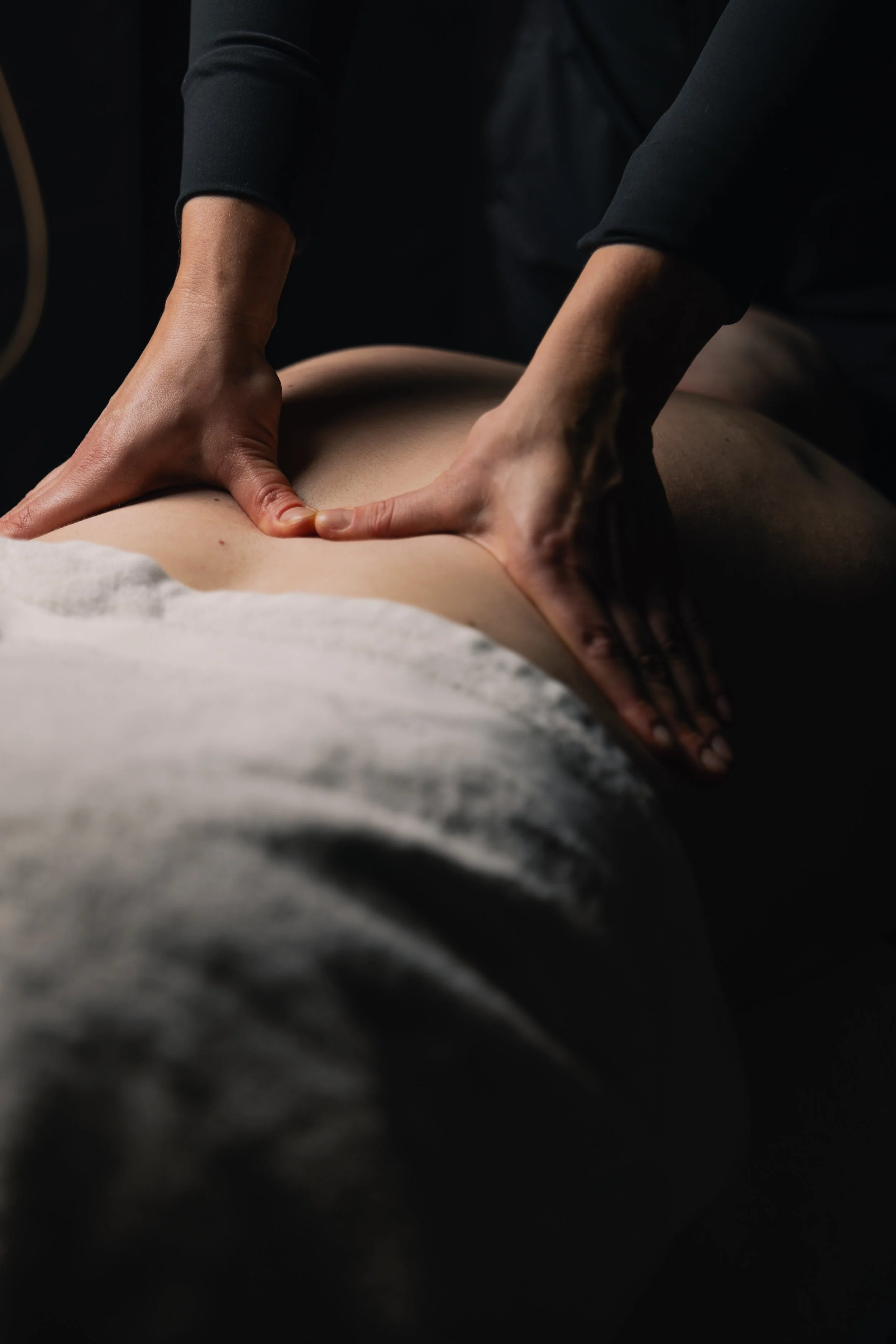 A massage therapist giving a back massage to a client lying face down.