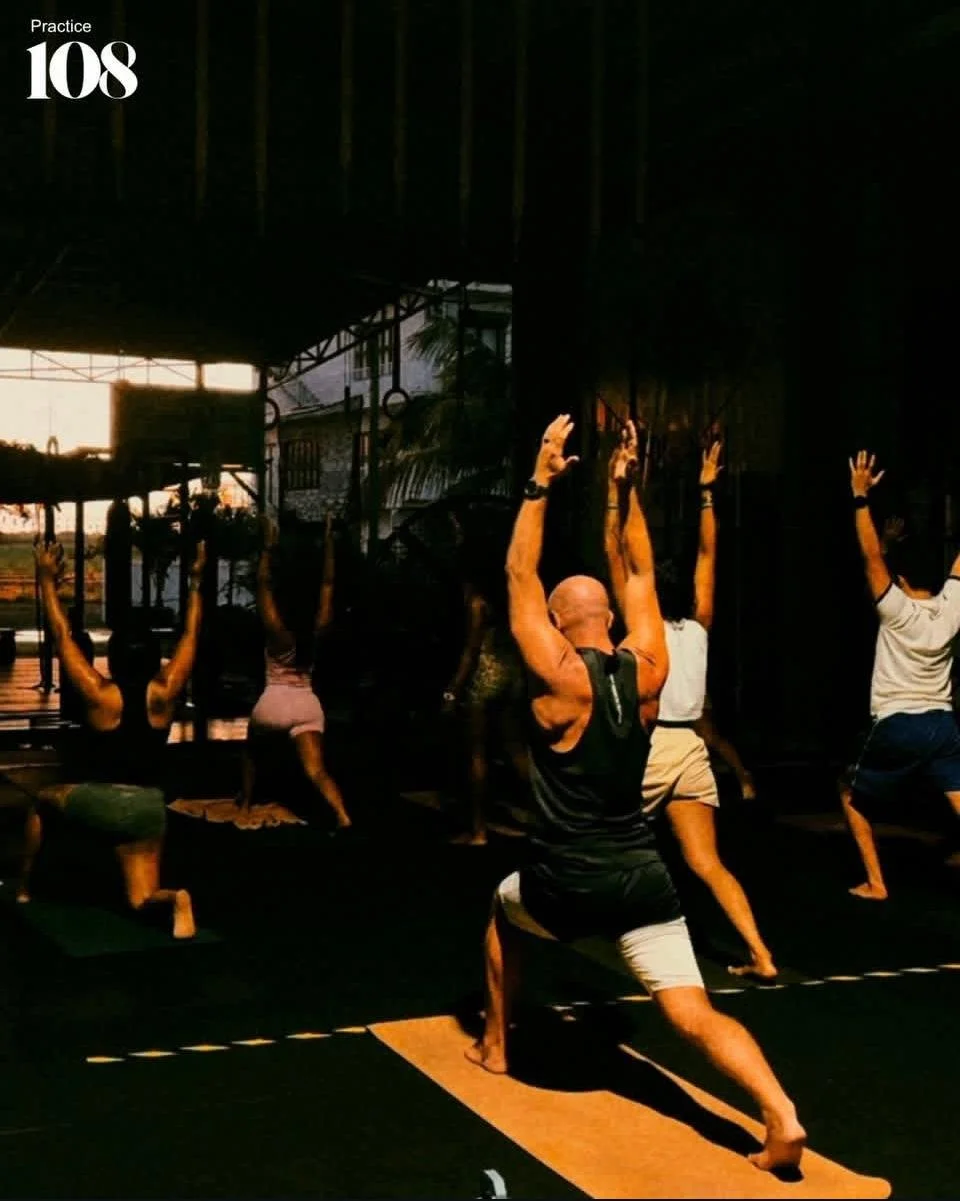 A person standing on rocks beside a clear, blue, natural pool in a lush, green forest.