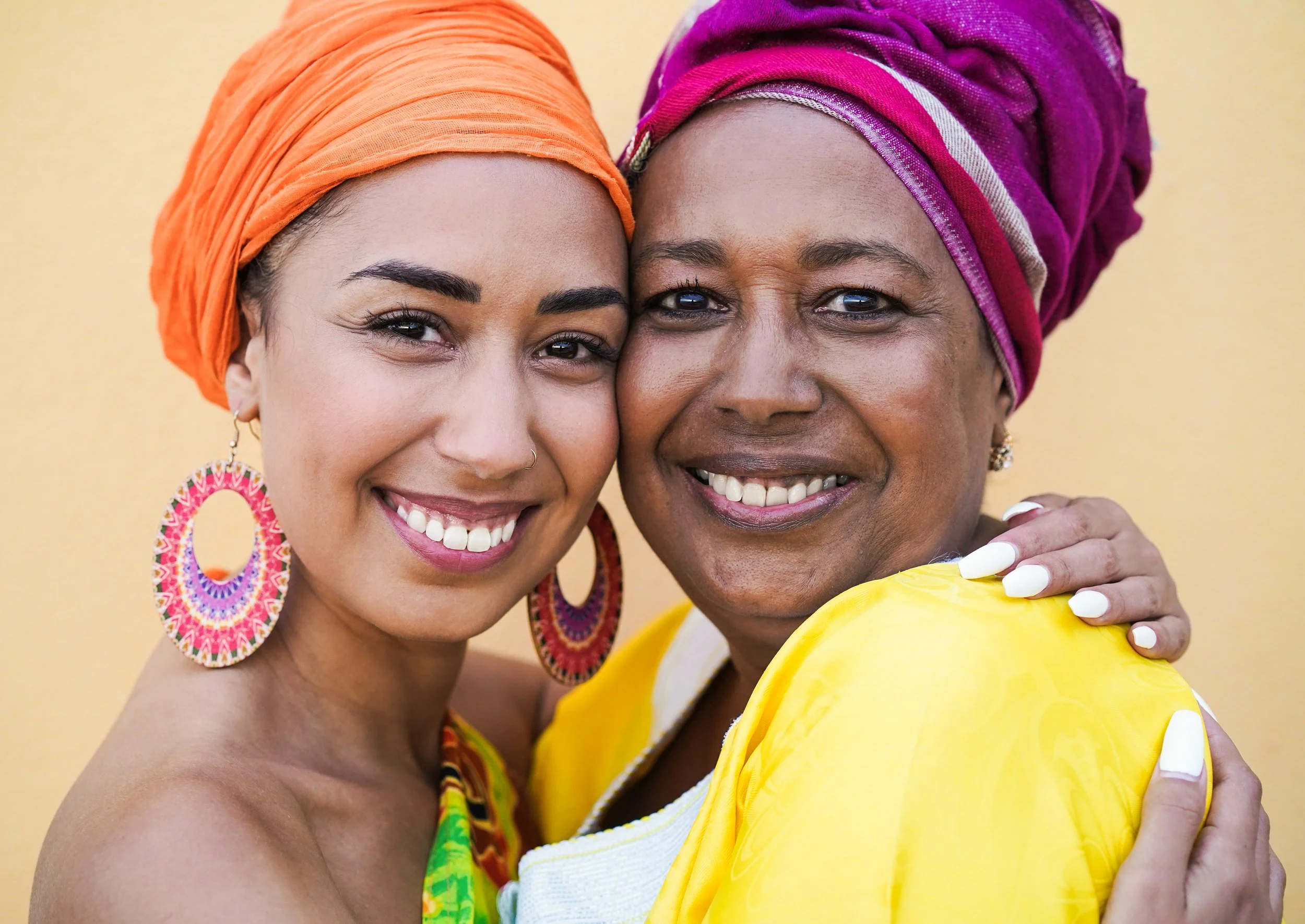 Two Black women are embracing each other looking at the camera.