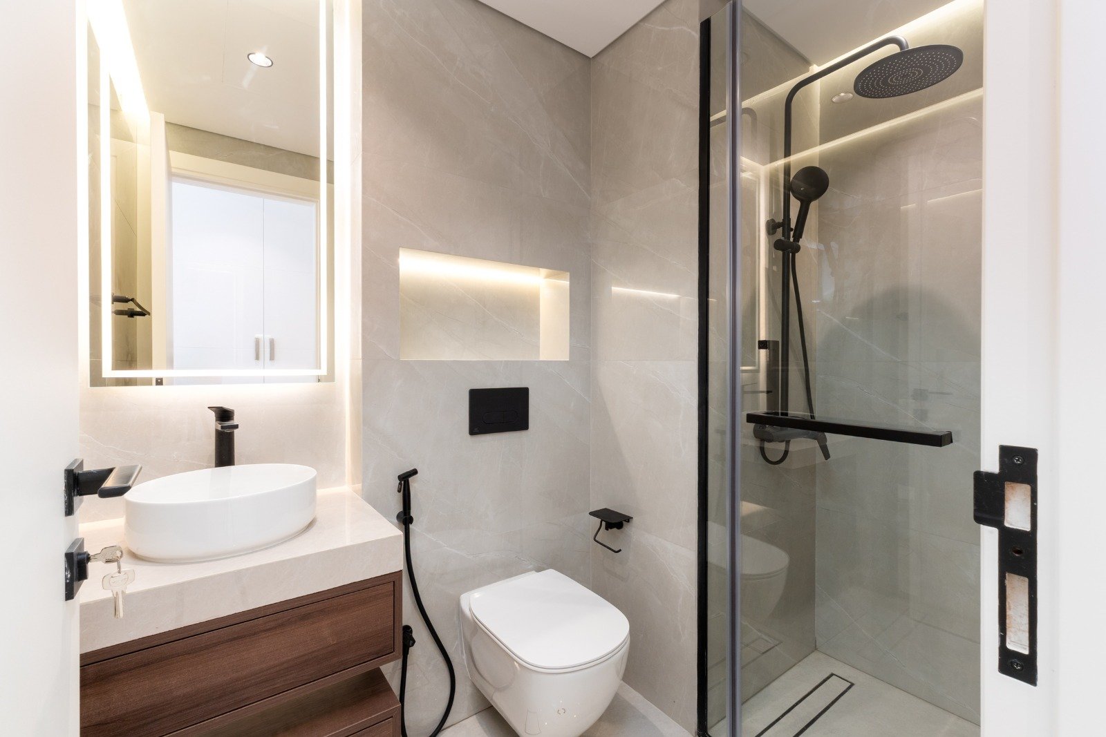 Modern bathroom with a walk-in shower, black fixtures, a white toilet, and a vanity with a vessel sink.