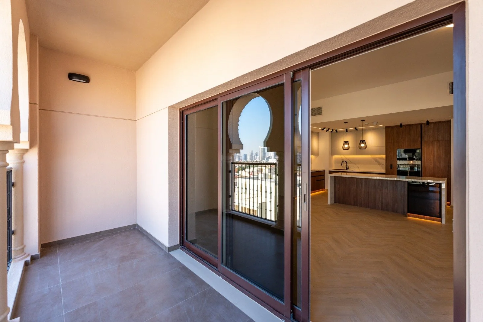 Balcony with a sliding glass door view of a modern kitchen and city skyline.
