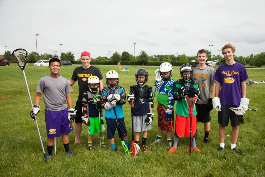 Junior Golden Eagles boys in lacrosse gear standing on a grassy field