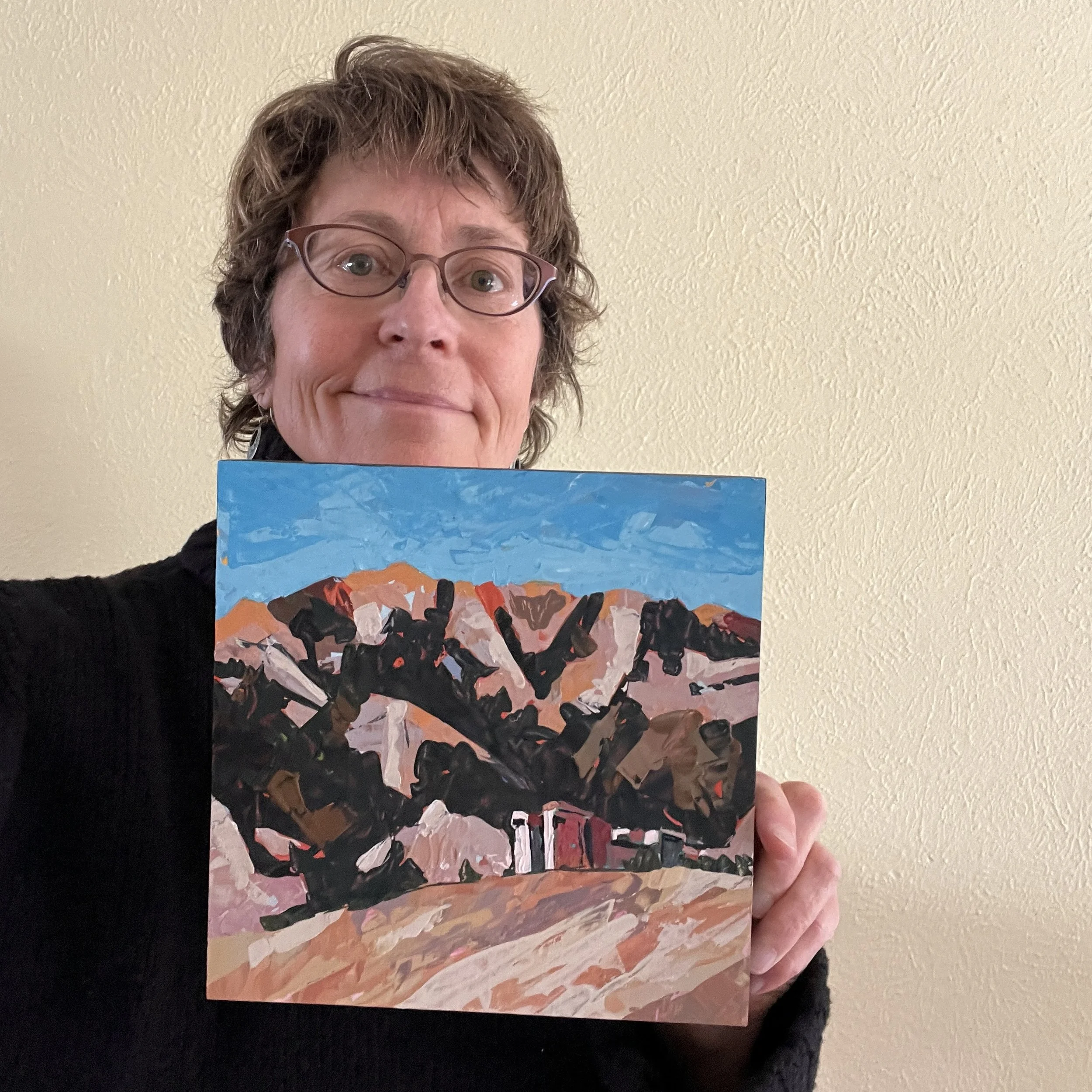 Lisa Seaman holding a small painting of NCAR