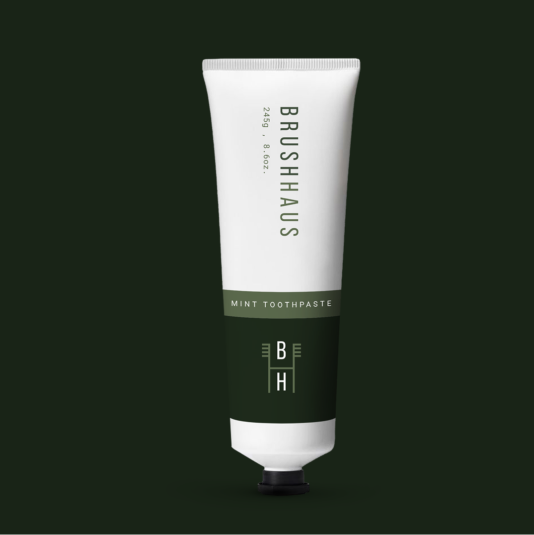 A tube of Brushhaus mint toothpaste against a dark green background.