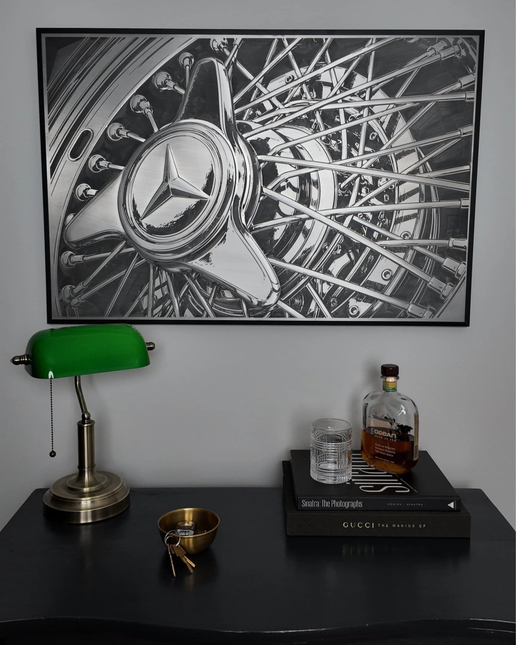 A black and white drawing of a Mercedes-Benz wheel with a star logo, displayed on a wall.