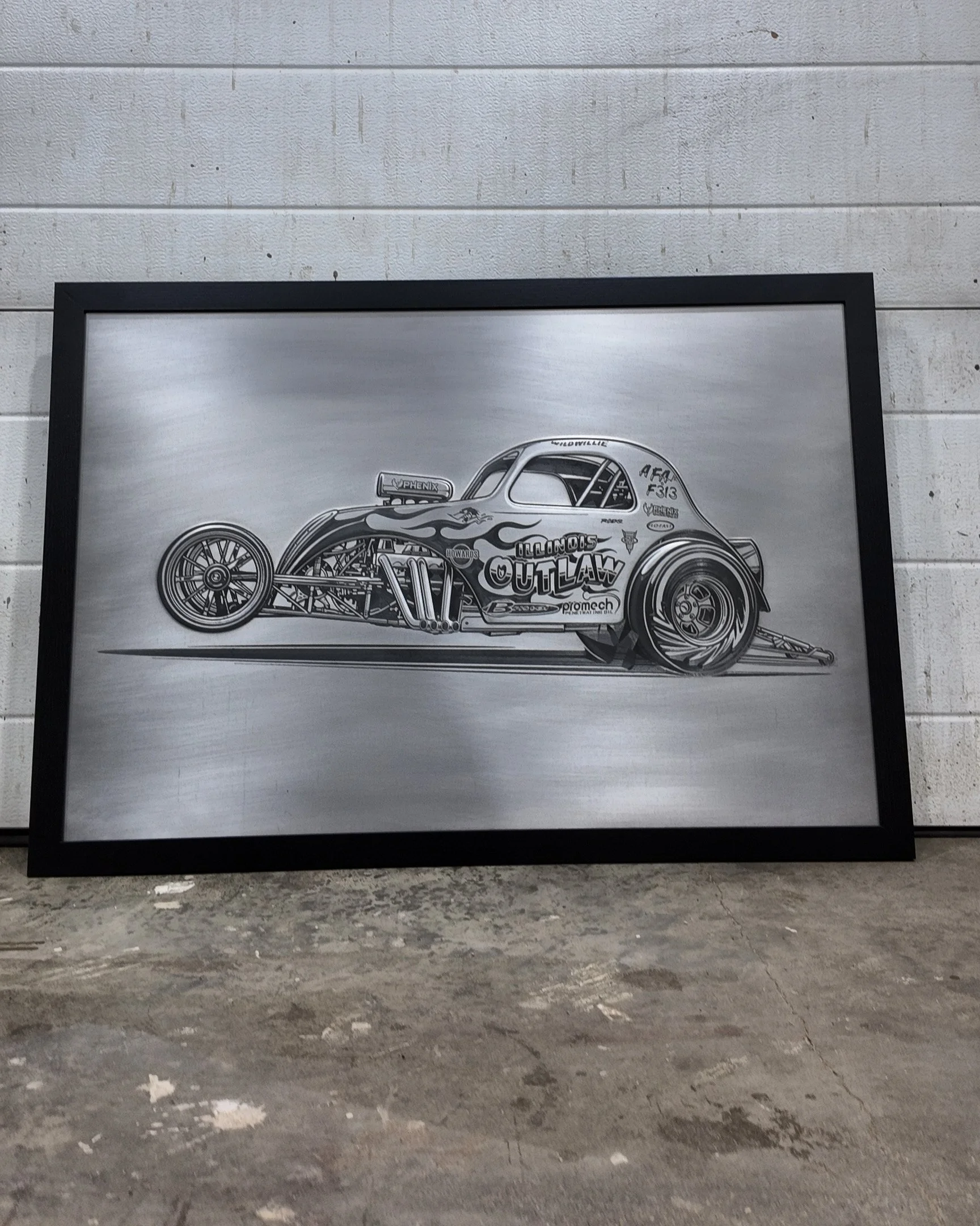 Framed black-and-white illustration of a vintage drag racing car on a gray textured wall, with a concrete floor beneath.