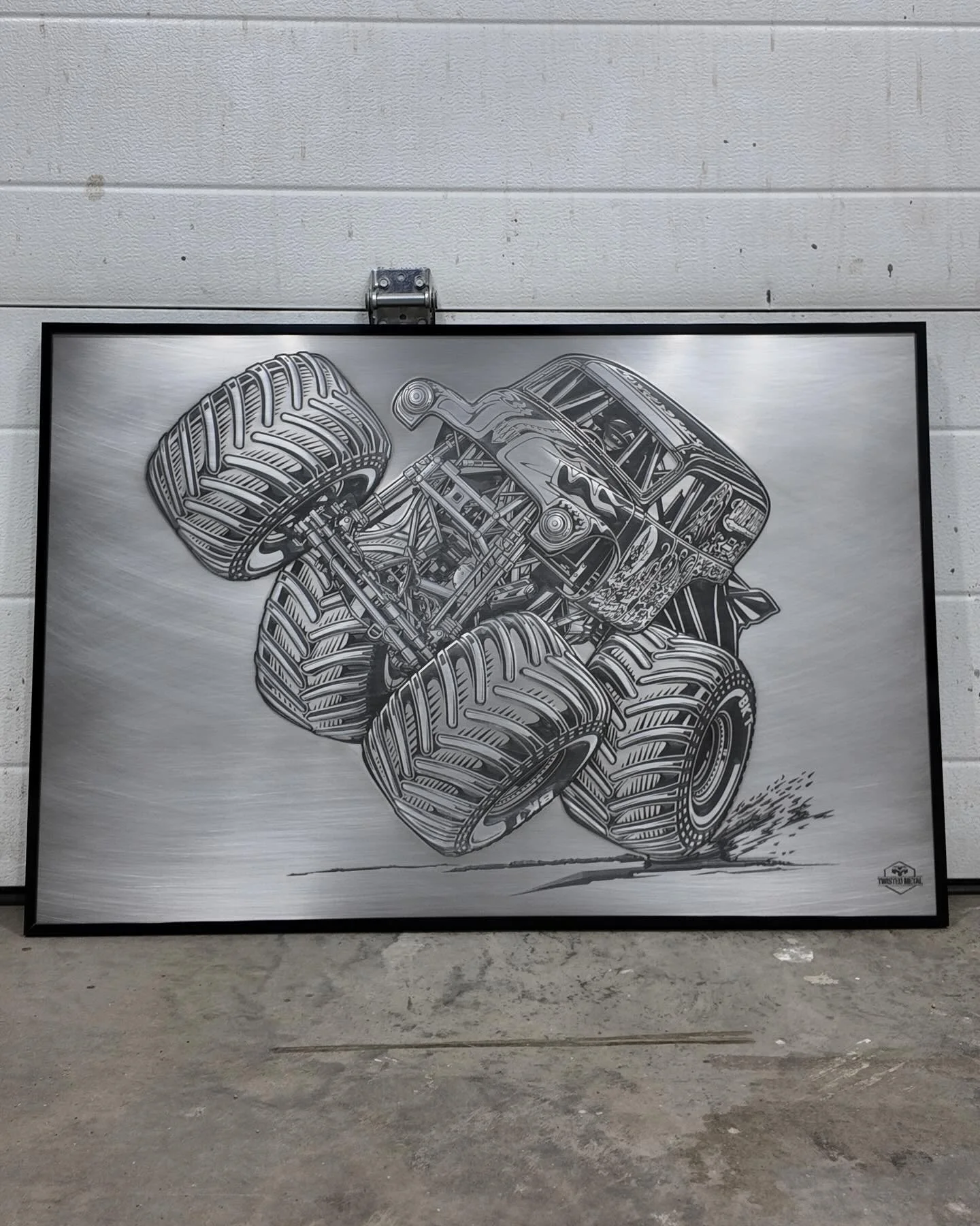 Black and white illustration of a monster truck with large tires, viewed from the side, on a gray background.