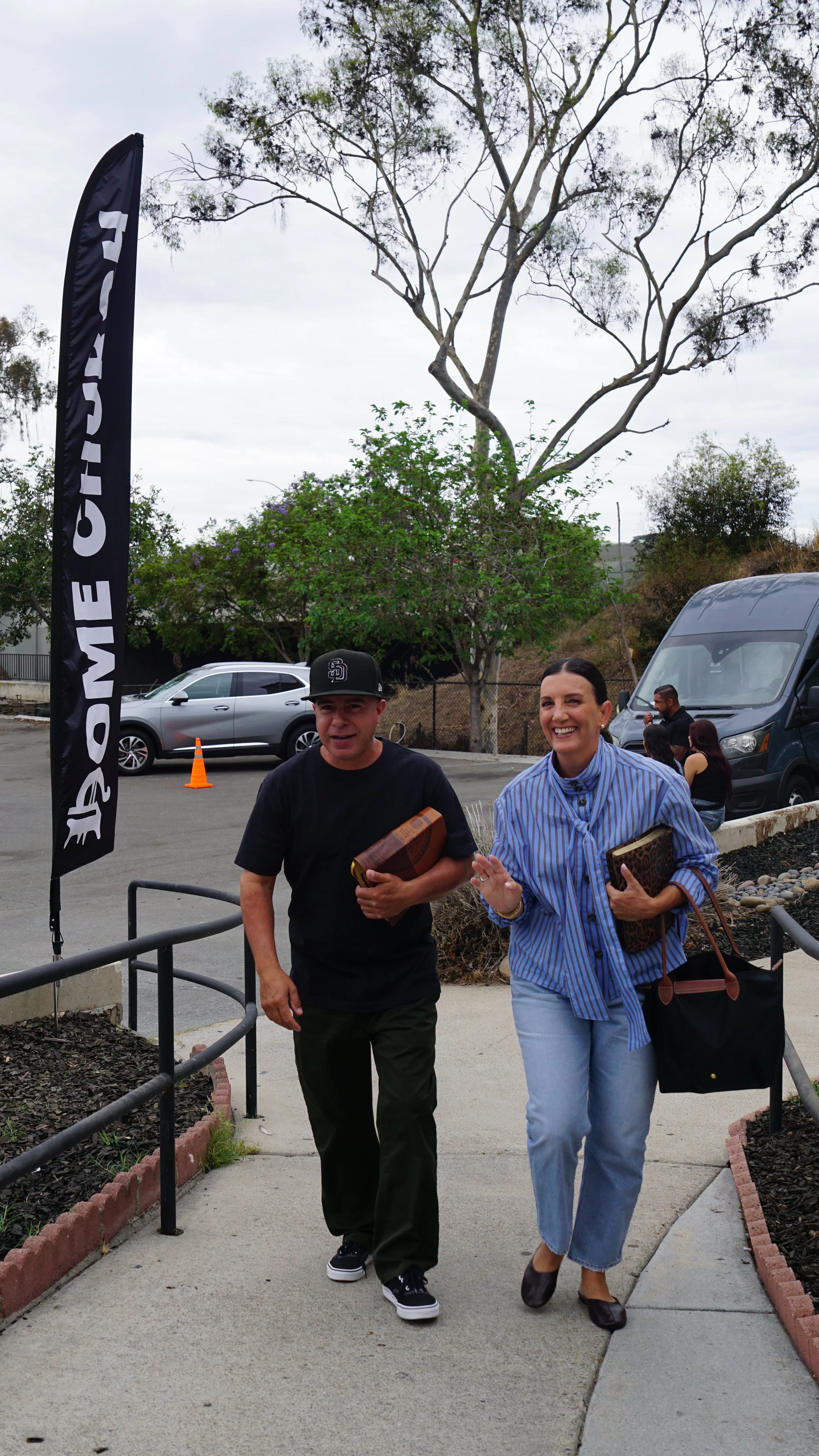 Two people arriving at Home Church San Diego carrying Bibles.