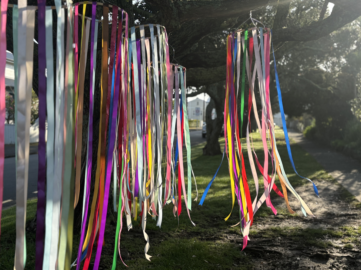 Colorful paper streamers hanging from a tree on a sunny day.