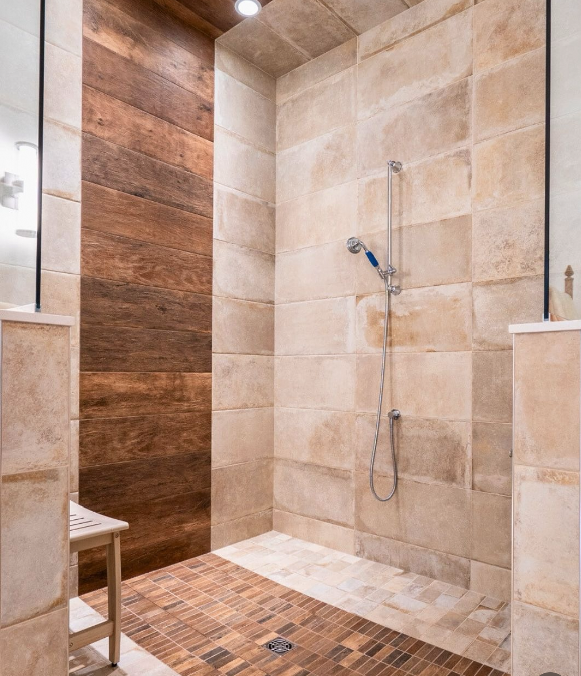 Ensuite shower with wood tile London, Ontario A modern shower area with beige and brown tiles, a hand-held shower head, and a small wooden shelf.