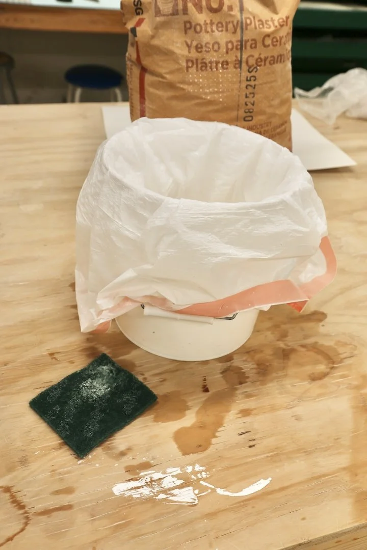 Bucket lined with trash bag &amp; filled with water for rinsing. 