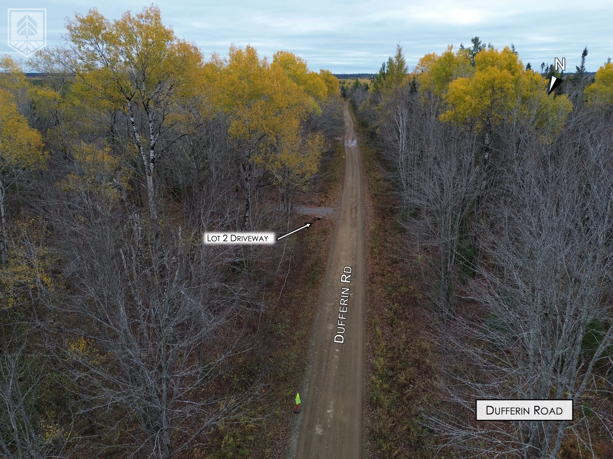 Aerial view of a dirt road called Dufferin Road stretched out into the distance, surrounded by leafless trees on either side with some trees showing yellow autumn foliage, under an overcast sky. Two labeled areas indicate 'Lot 2 Driveway' on the left