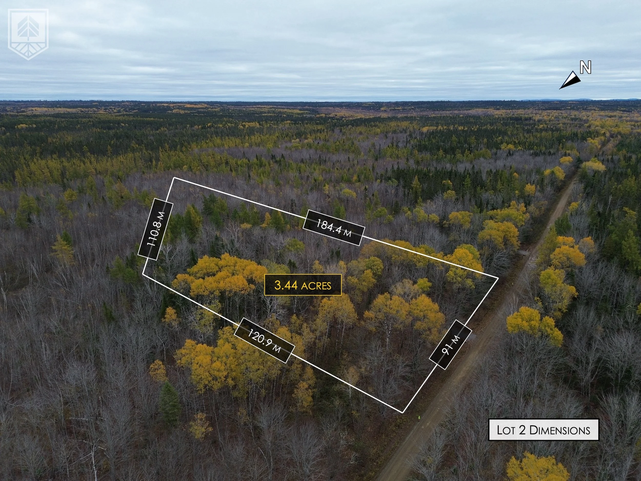 Aerial view of a rectangular wooded lot outlined with white lines, with four sides labeled with measurements, and a dirt road on the right side. The lot covers 3.44 acres and is surrounded by dense forest with a mix of green and leafless trees, under
