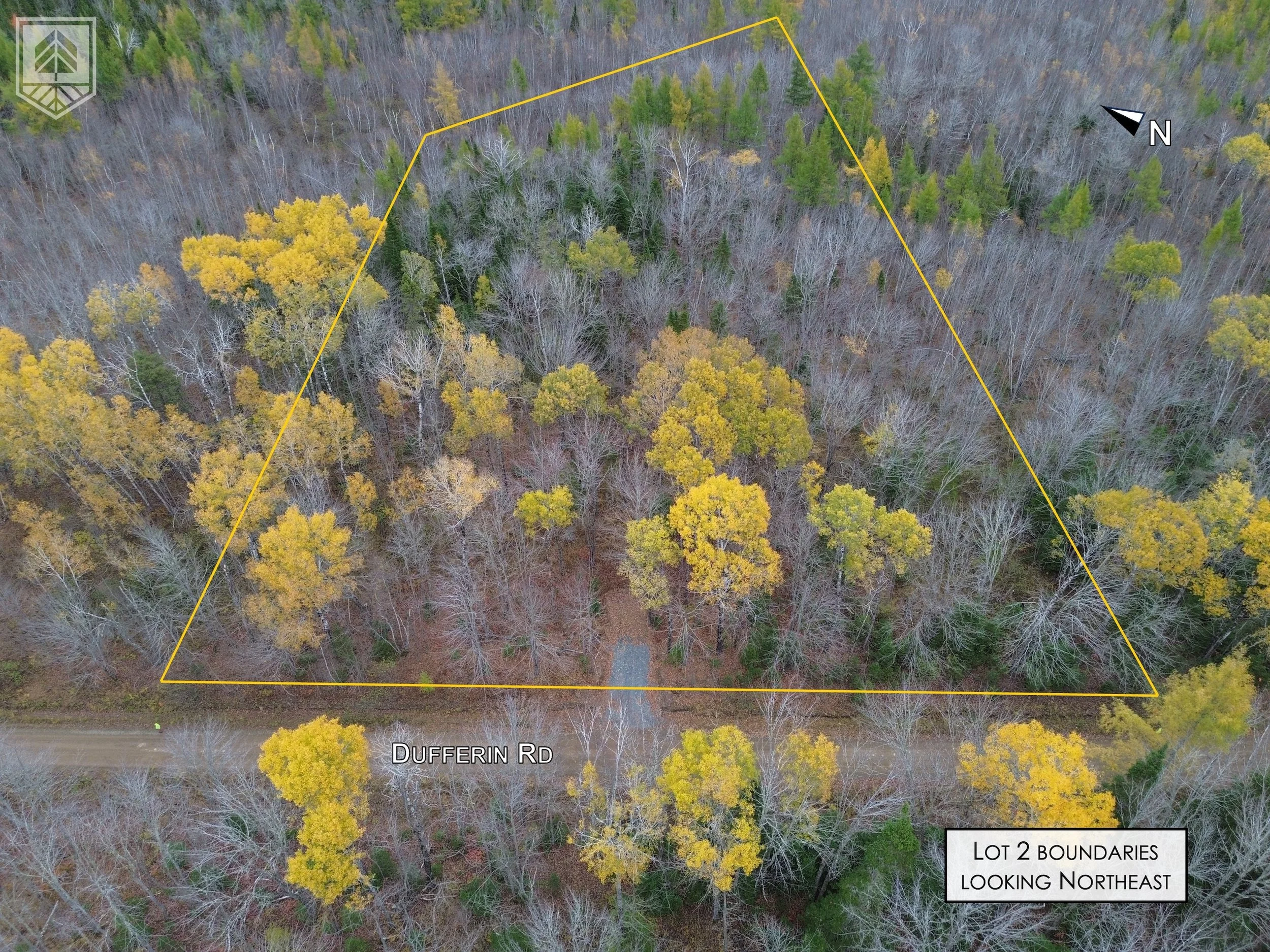 Aerial view of a wooded lot outlined in yellow, with trees showing fall foliage and some without leaves. Dufferin Road runs along the front of the lot. The image includes a north direction indicator and a label reading, 'Lot 2 Boundaries Looking Nort