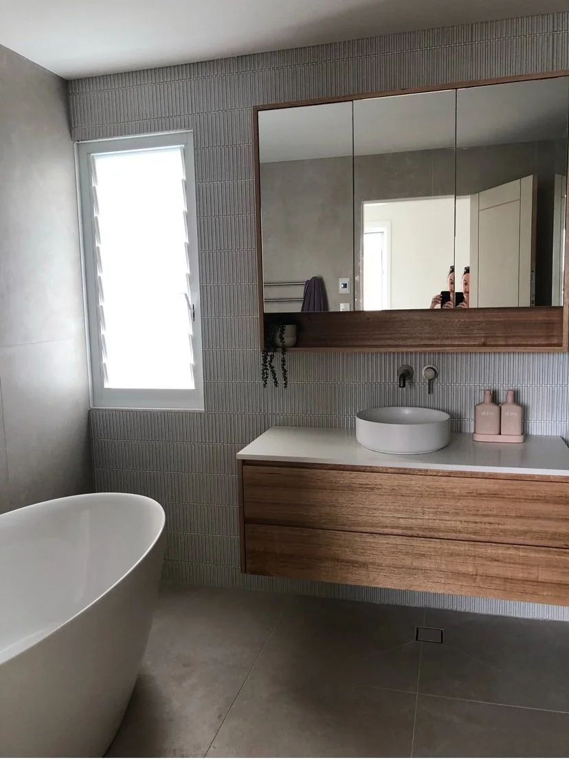 modern bathroom with standalone bathtub and floating vanity, timber doors and brass finishings