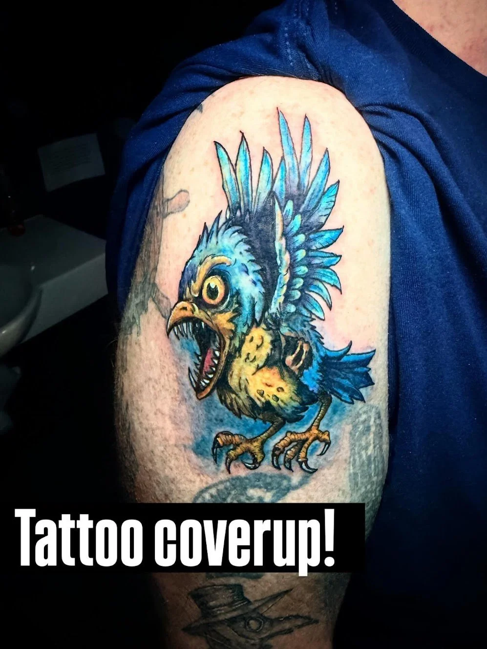 Colorful tattoo of a mythical bird with fierce expression, feathers, and sharp talons on person's arm, with text overlay reading 'Tattoo coverup!'.