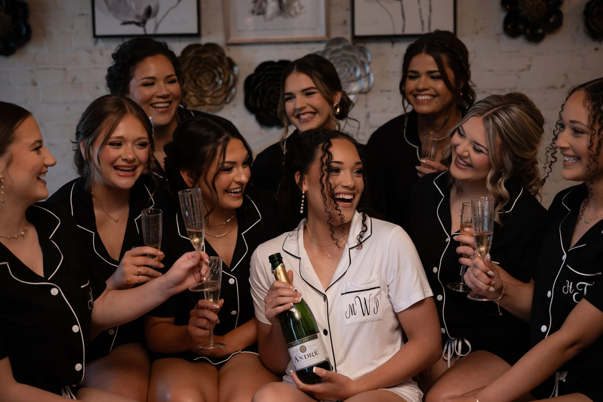 A group of friends celebrating with champagne, women in pajamas, smiling and enjoying each other's company indoors.
