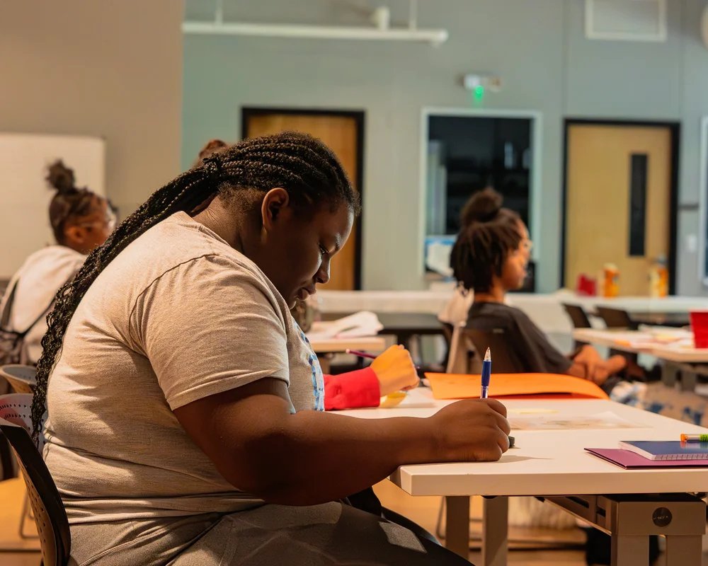 A teen writing in a notebook during a DOPE workshop