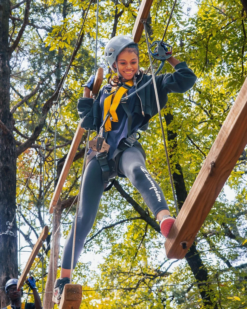 A teen smiling while crossing an elevated ropes course