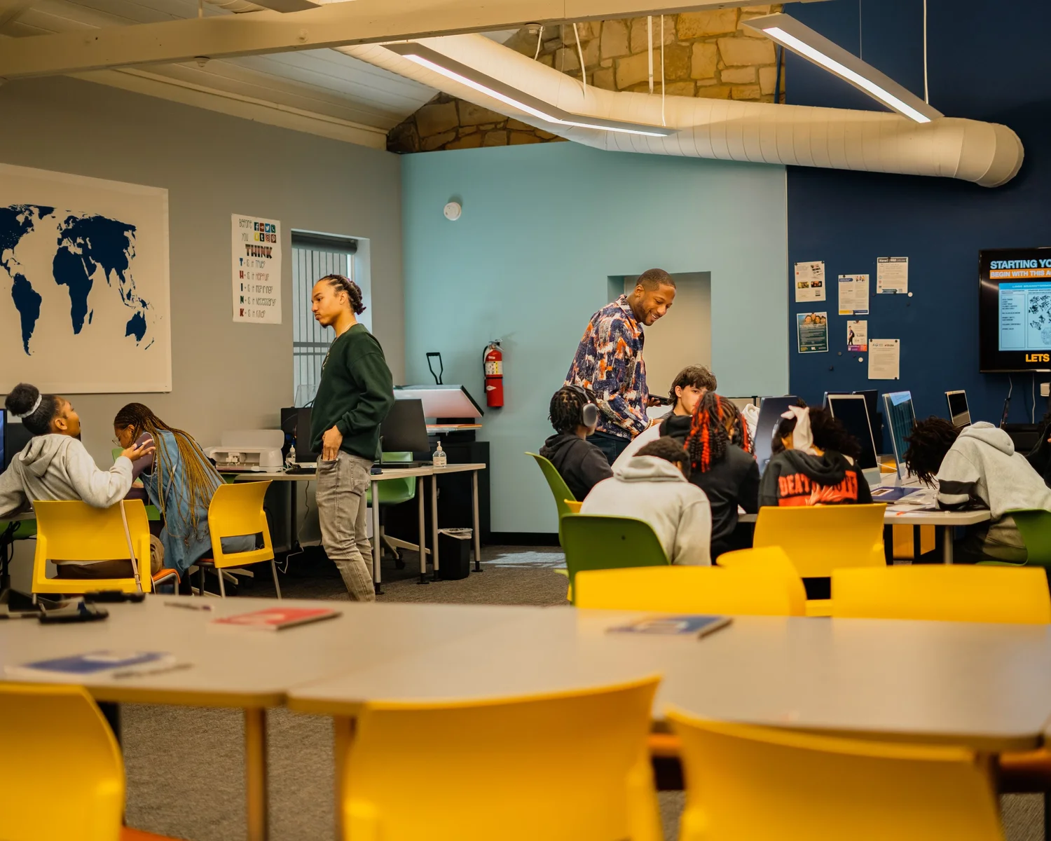 Teens working with facilitators around classroom tables
