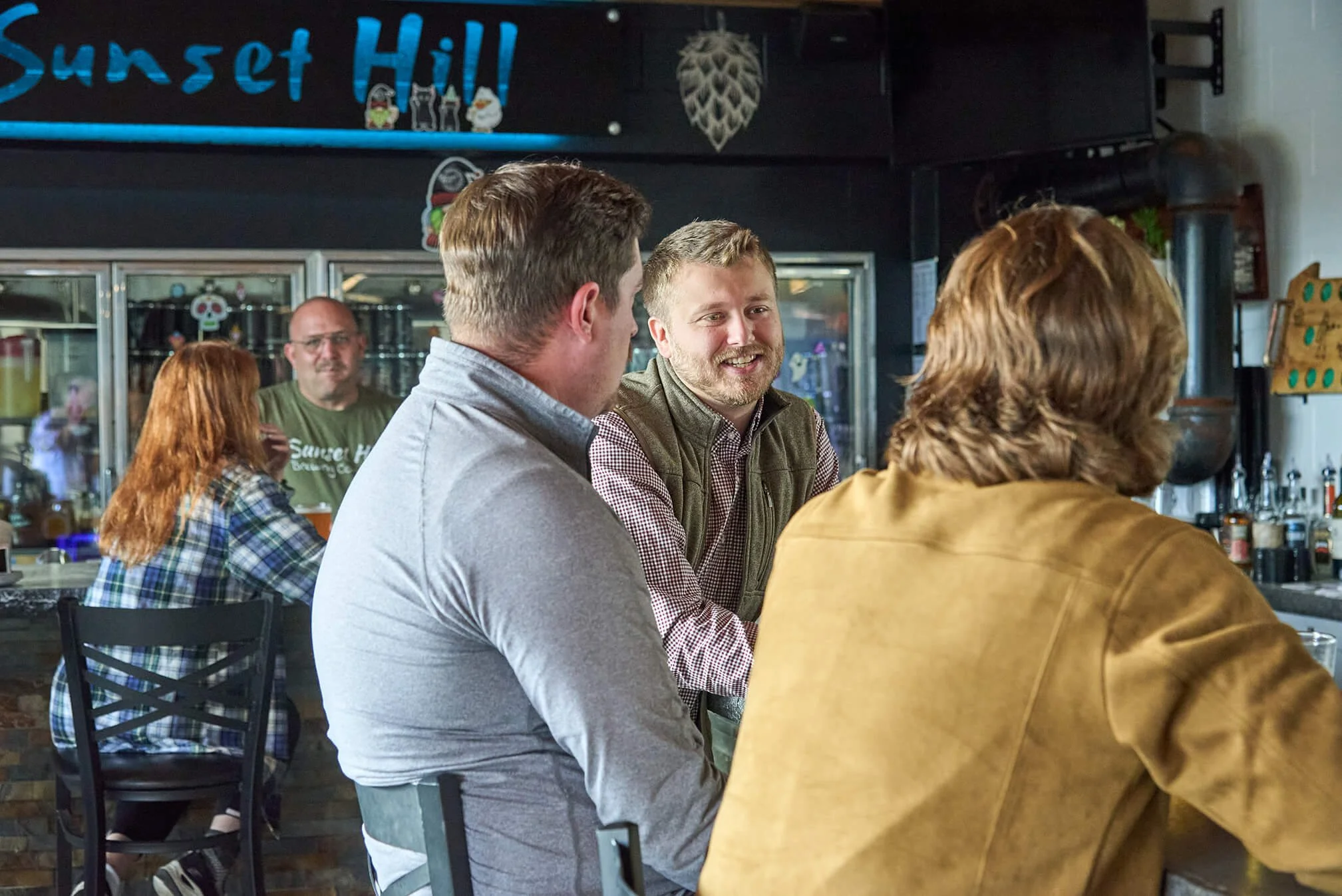 Chris sitting at a bar engaging in conversation, with a bartender in the background